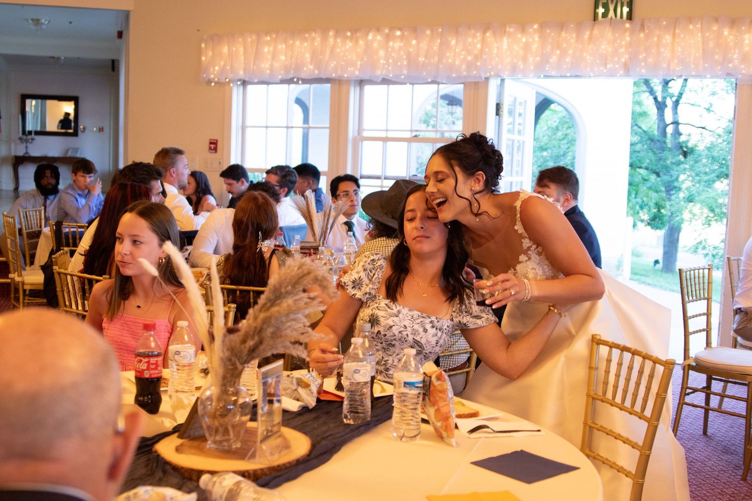 Wedding reception dining area with tables set for guests in bright indoor venue.