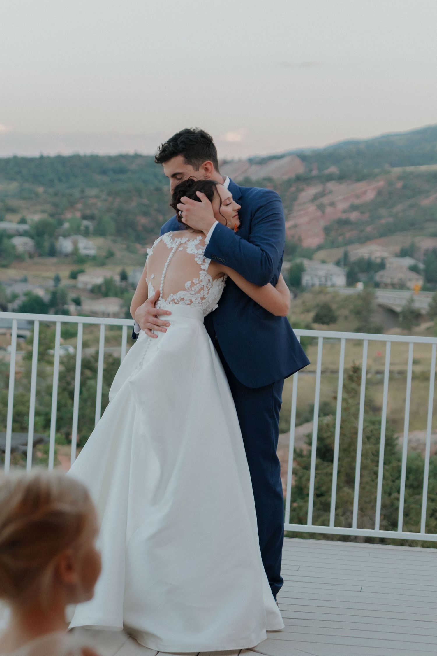 Intimate embrace shared during outdoor wedding celebration with scenic mountain views.