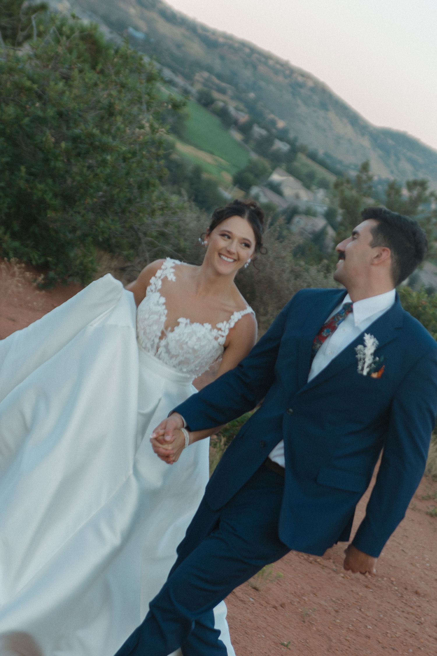Newlyweds share joyful moments during outdoor wedding photography session in mountain setting.