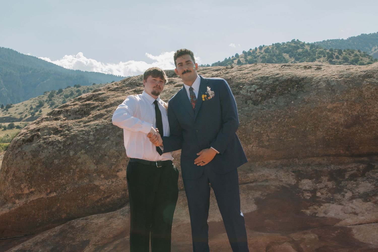 Wedding party posing against scenic mountain landscape with red rock formations.