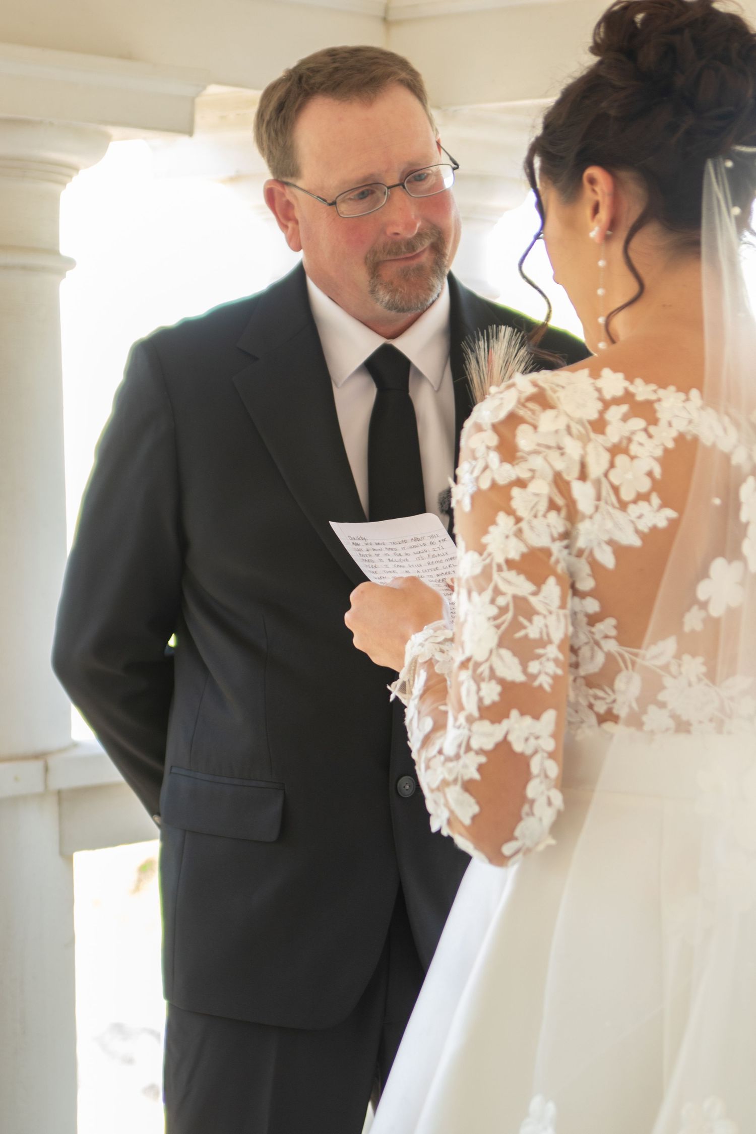 Emotional first look moment between couple on a bright white porch.
