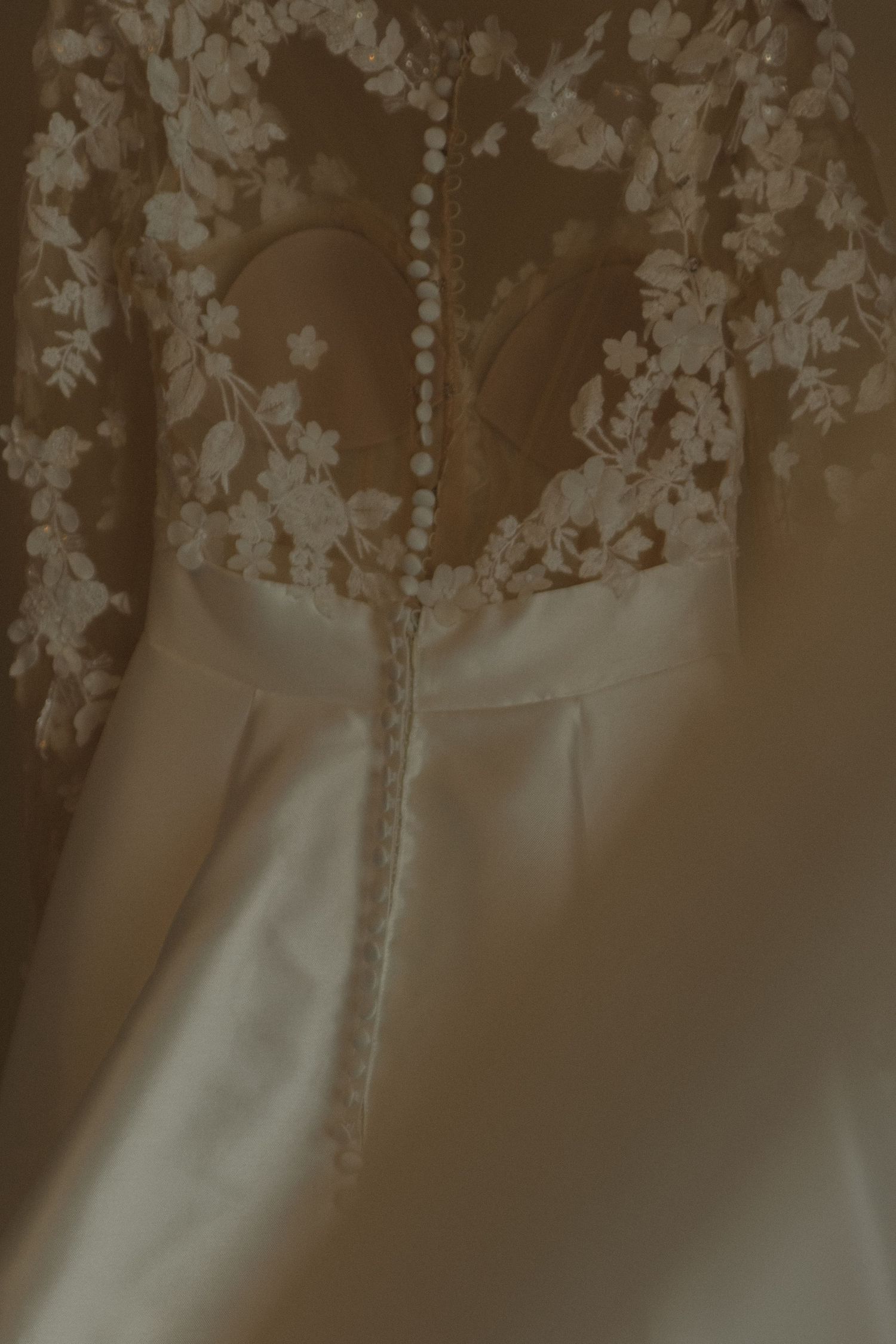 Close-up detail of delicate lace and fabric patterns on a white wedding gown.