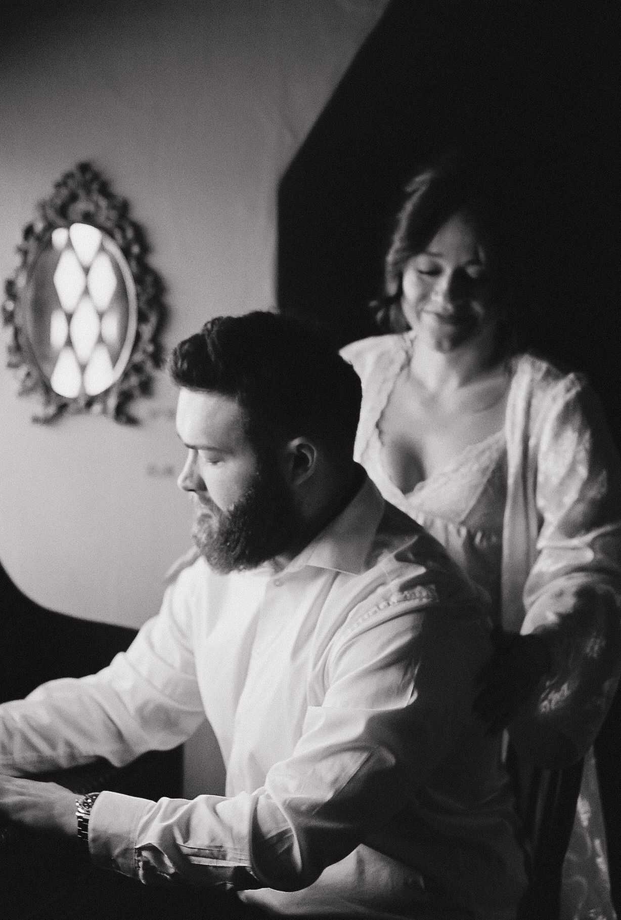 A black and white candid moment between a couple sitting together indoors.