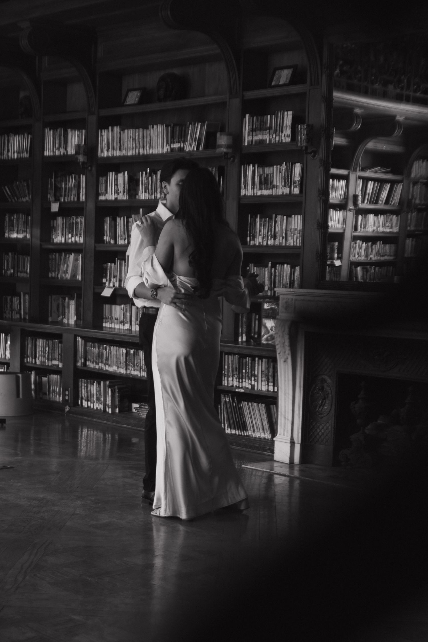 Black and white romantic sequence showing a couple dancing intimately between library bookshelves.