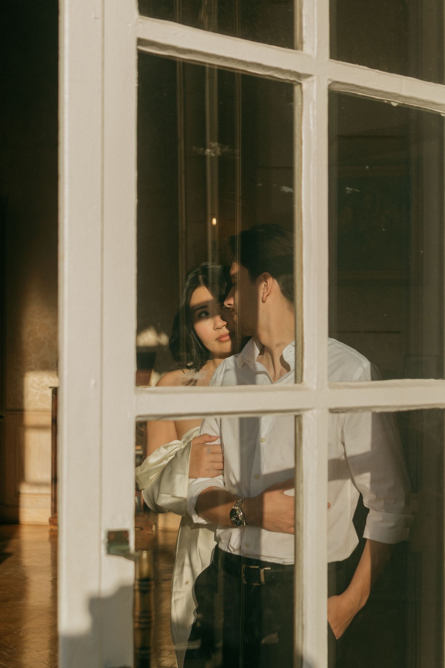 Light streams through white window panes onto figures in an indoor setting.