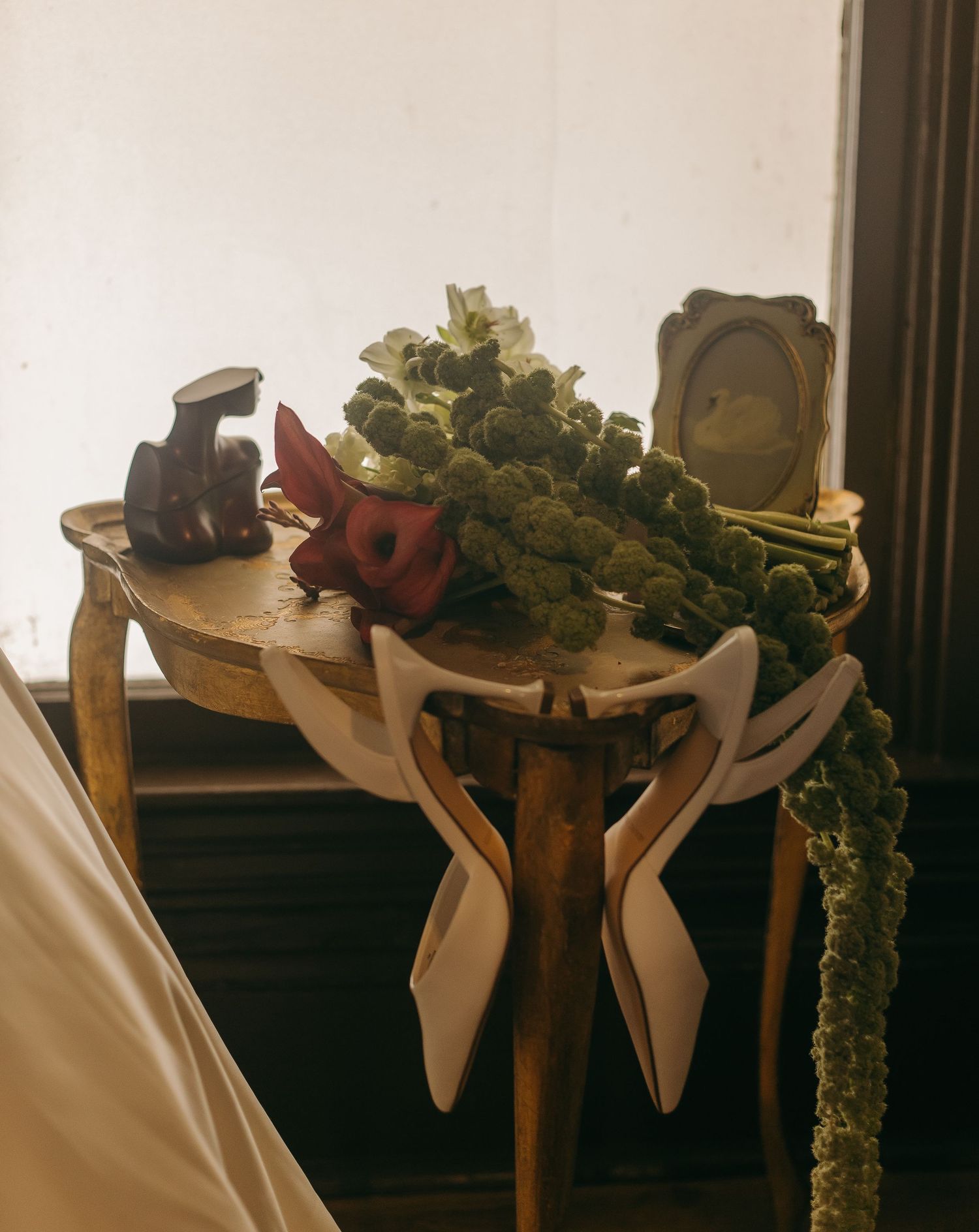 Wedding accessories and floral arrangements displayed on wooden furniture.