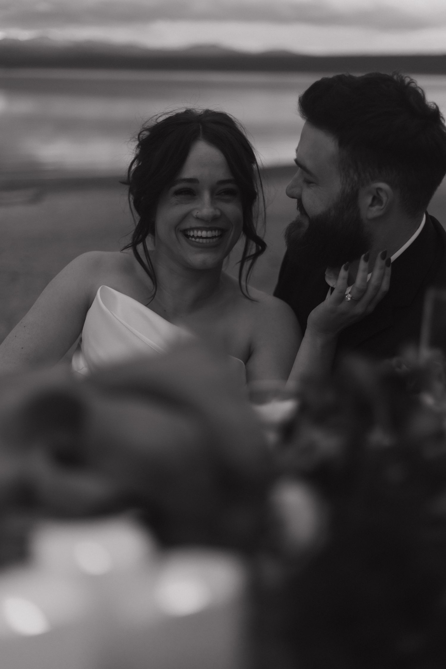 Black and white candid wedding moment captured against scenic backdrop.