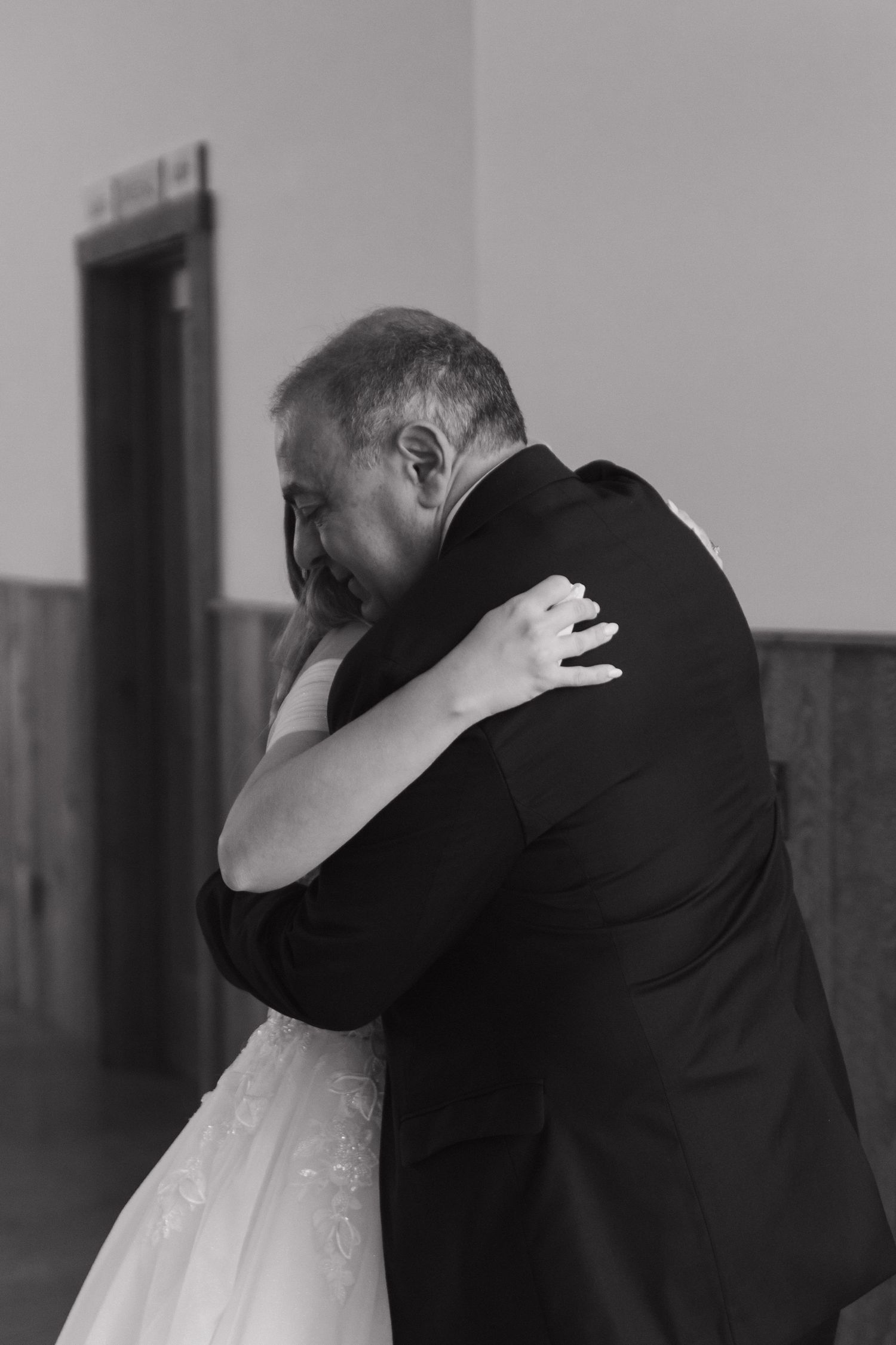 An intimate black and white wedding moment captured in an indoor setting.