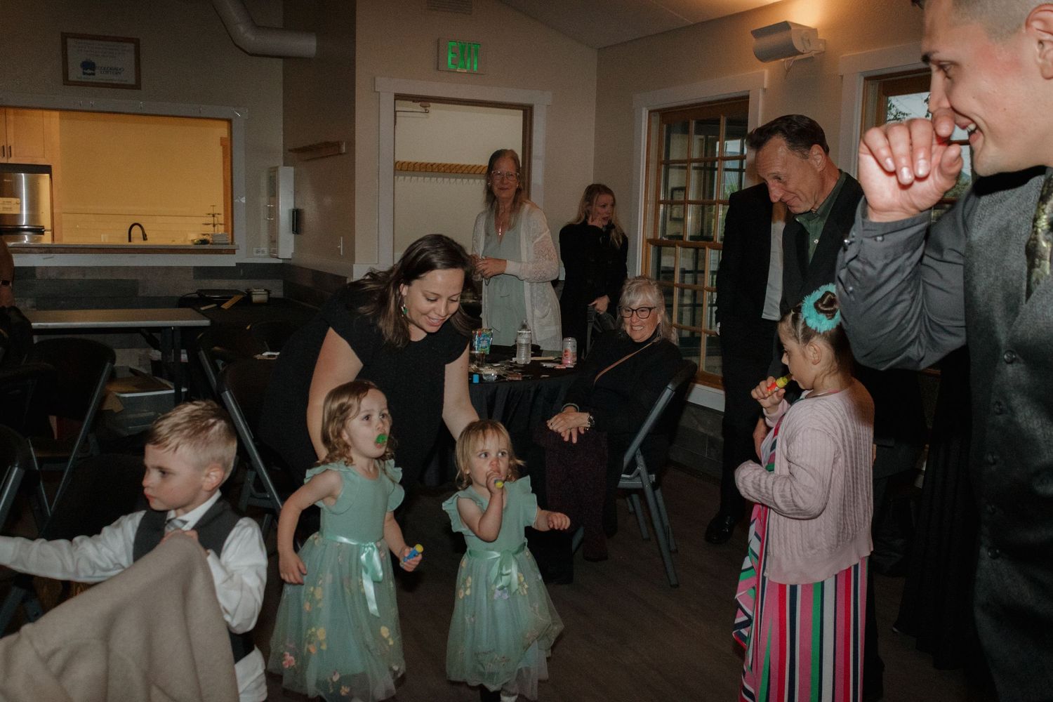 Group of wedding guests dancing and celebrating under green party lights at reception.