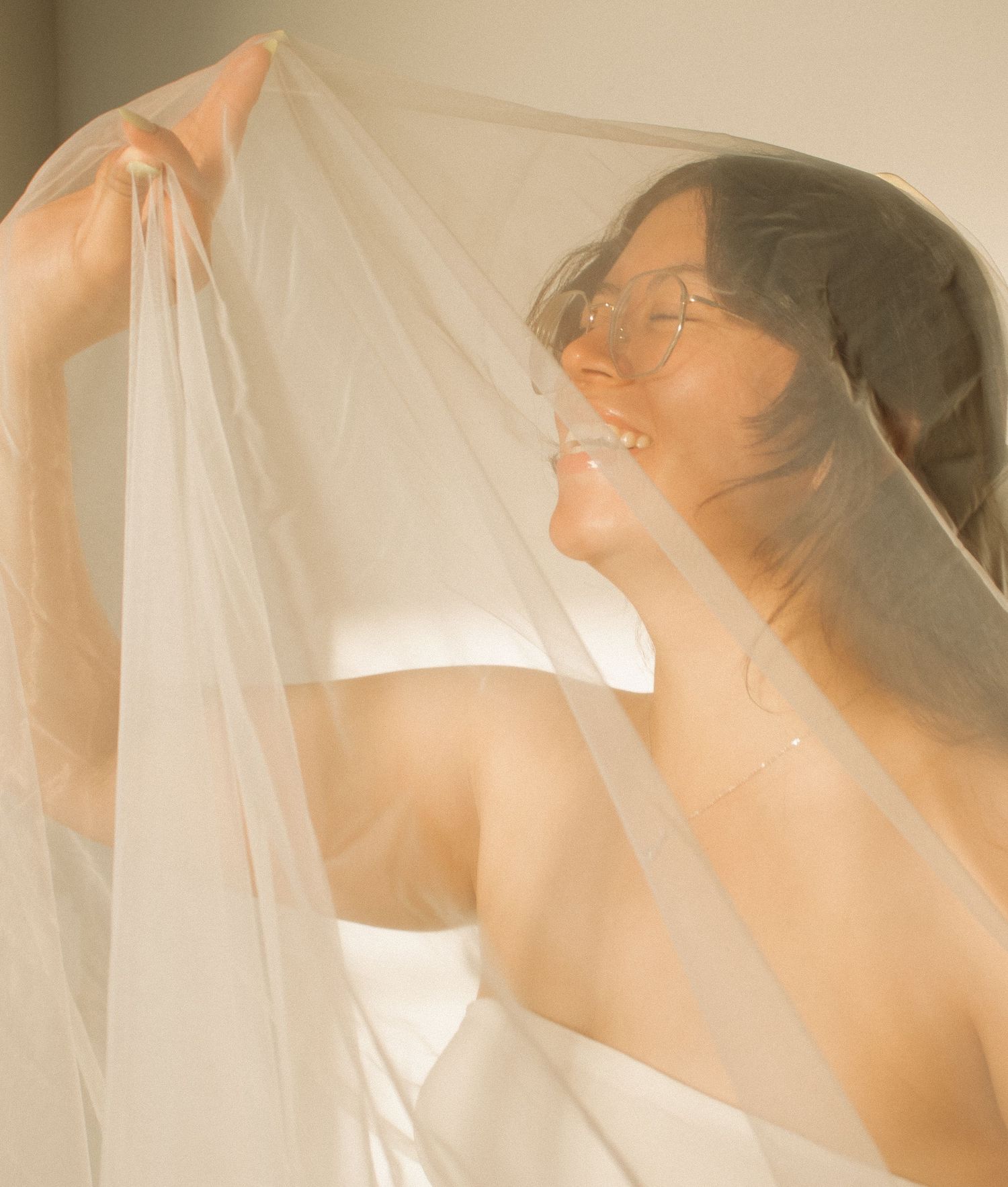 Ethereal bridal portrait through sheer veil with soft natural lighting.