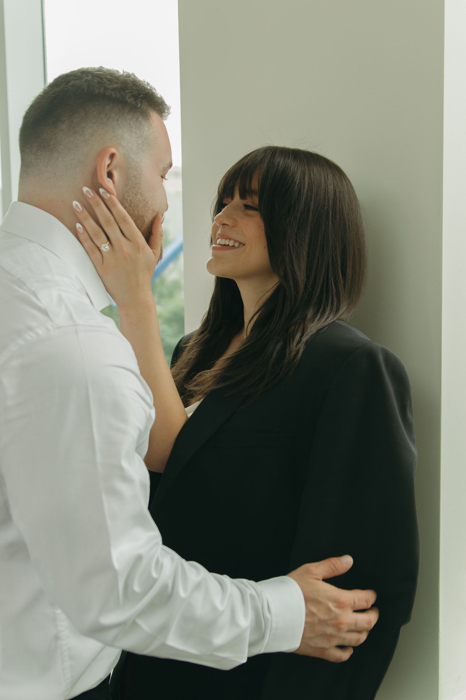 Tender embrace captured against minimalist white interior with natural lighting.