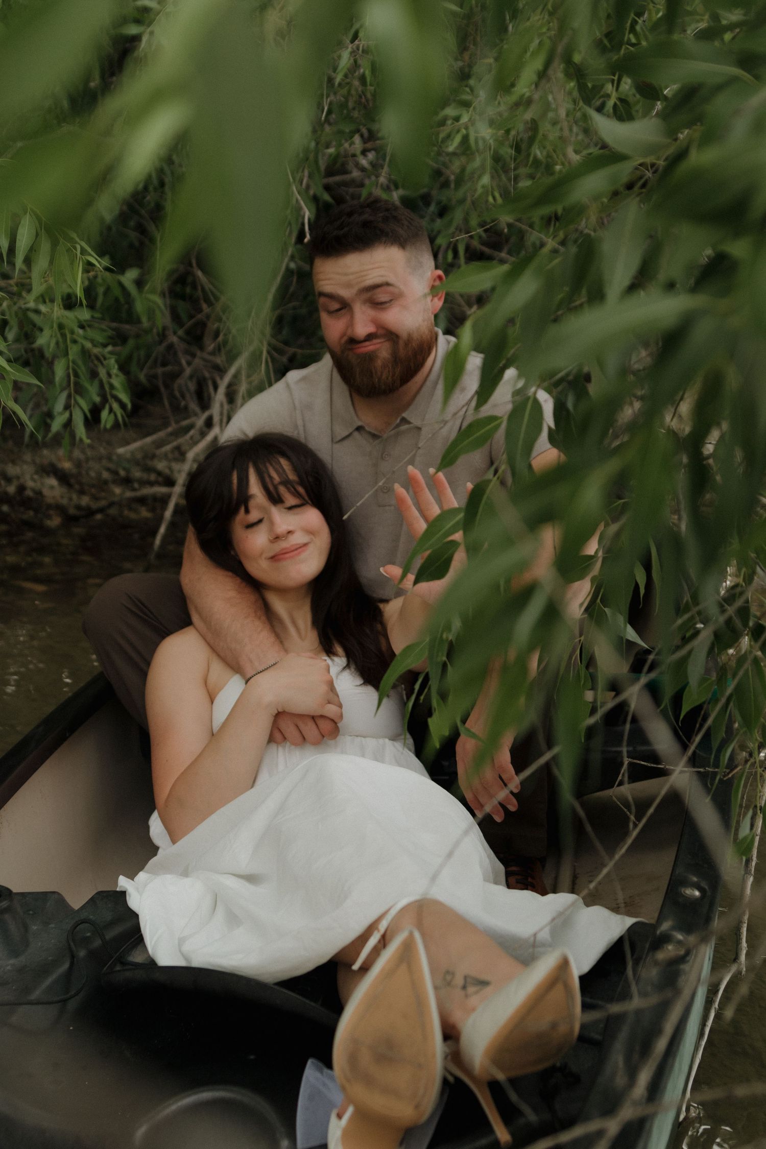 A tender embrace in a canoe surrounded by lush green foliage.