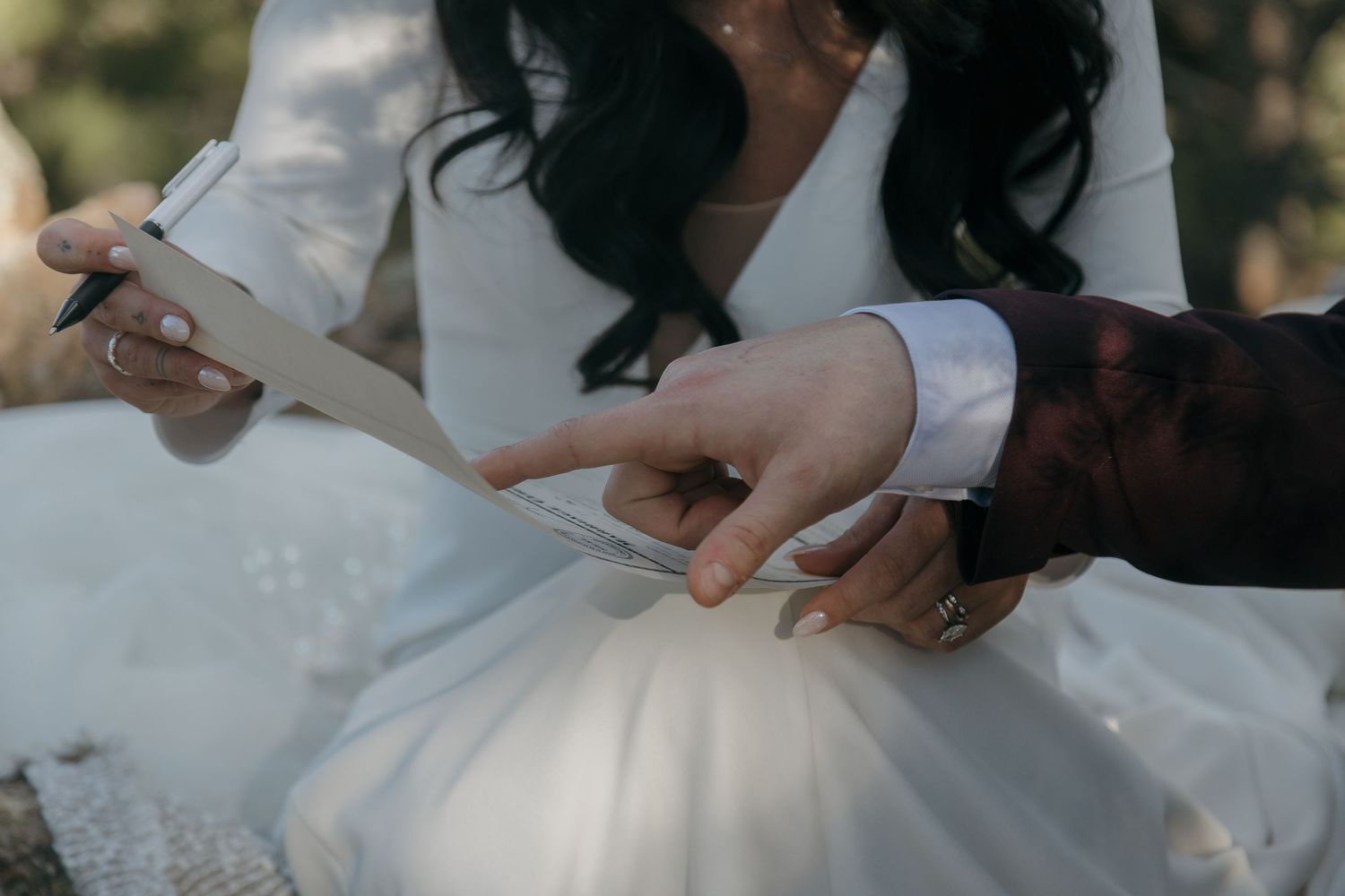Close-up of couple reading wedding vows from paper cards during intimate outdoor elopement ceremony.