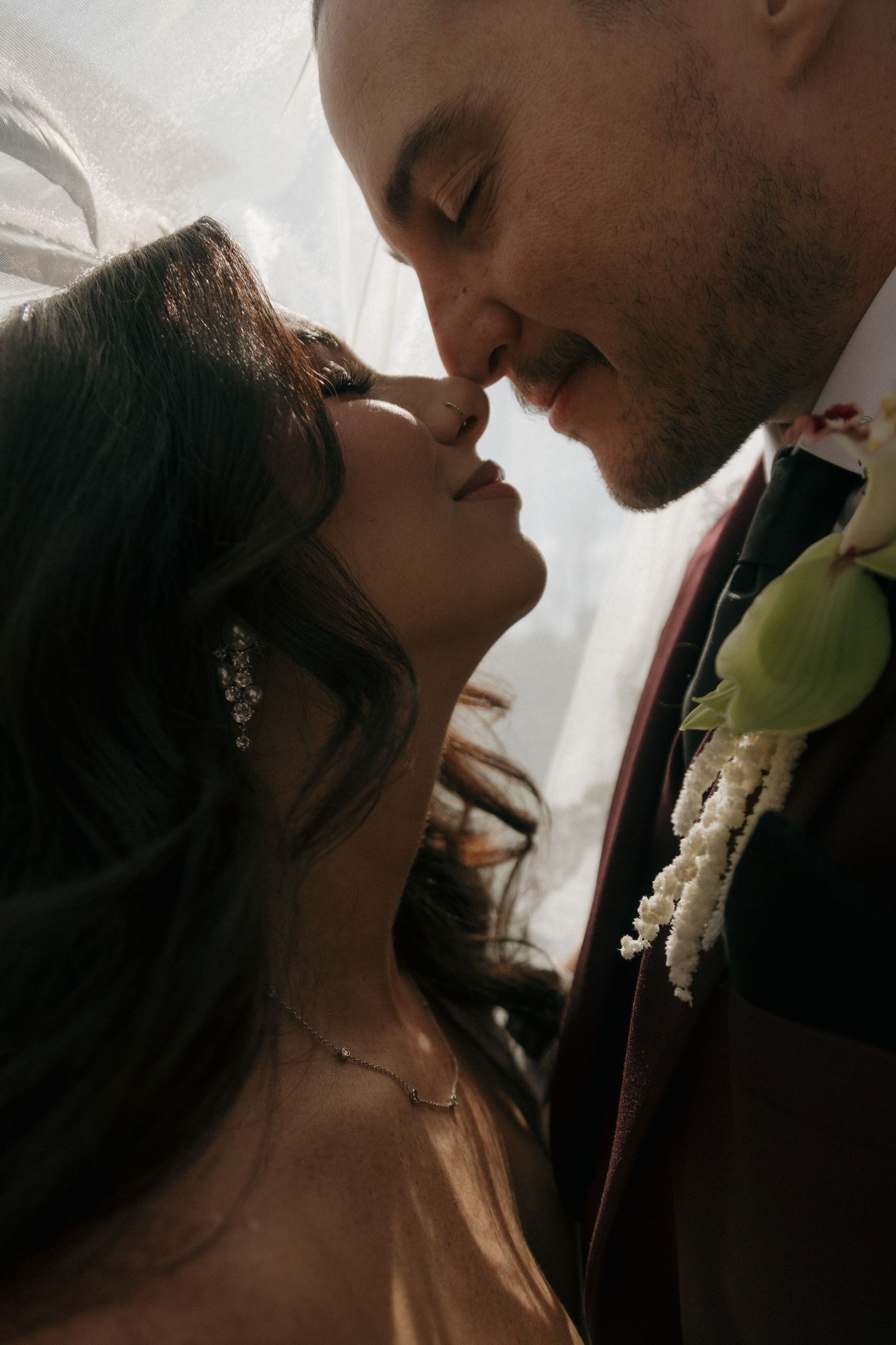 Intimate close-up of bride and groom sharing a romantic kiss under a flowing veil.