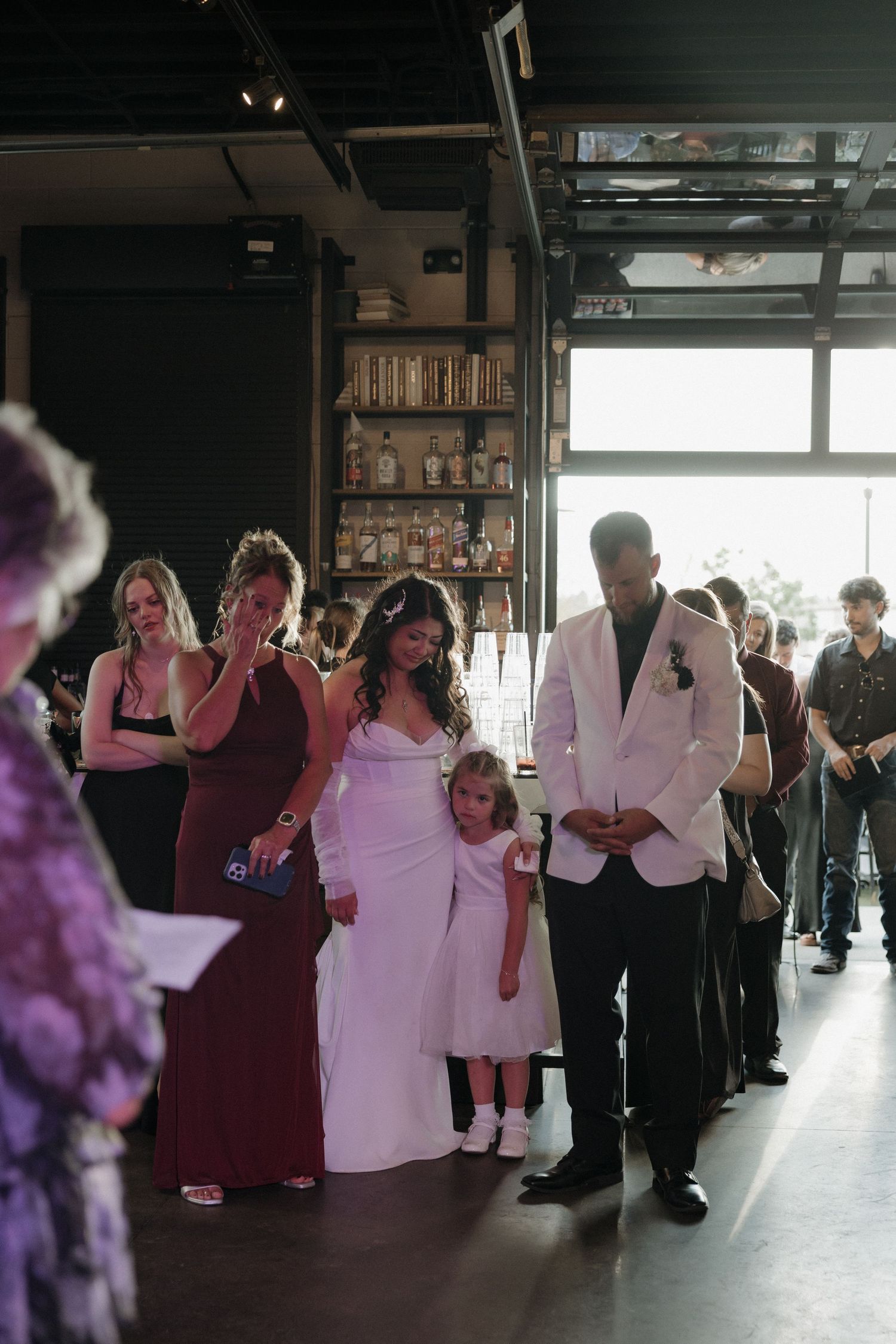 Bride in white gown walks the aisle with groom in white jacket and flower girl.