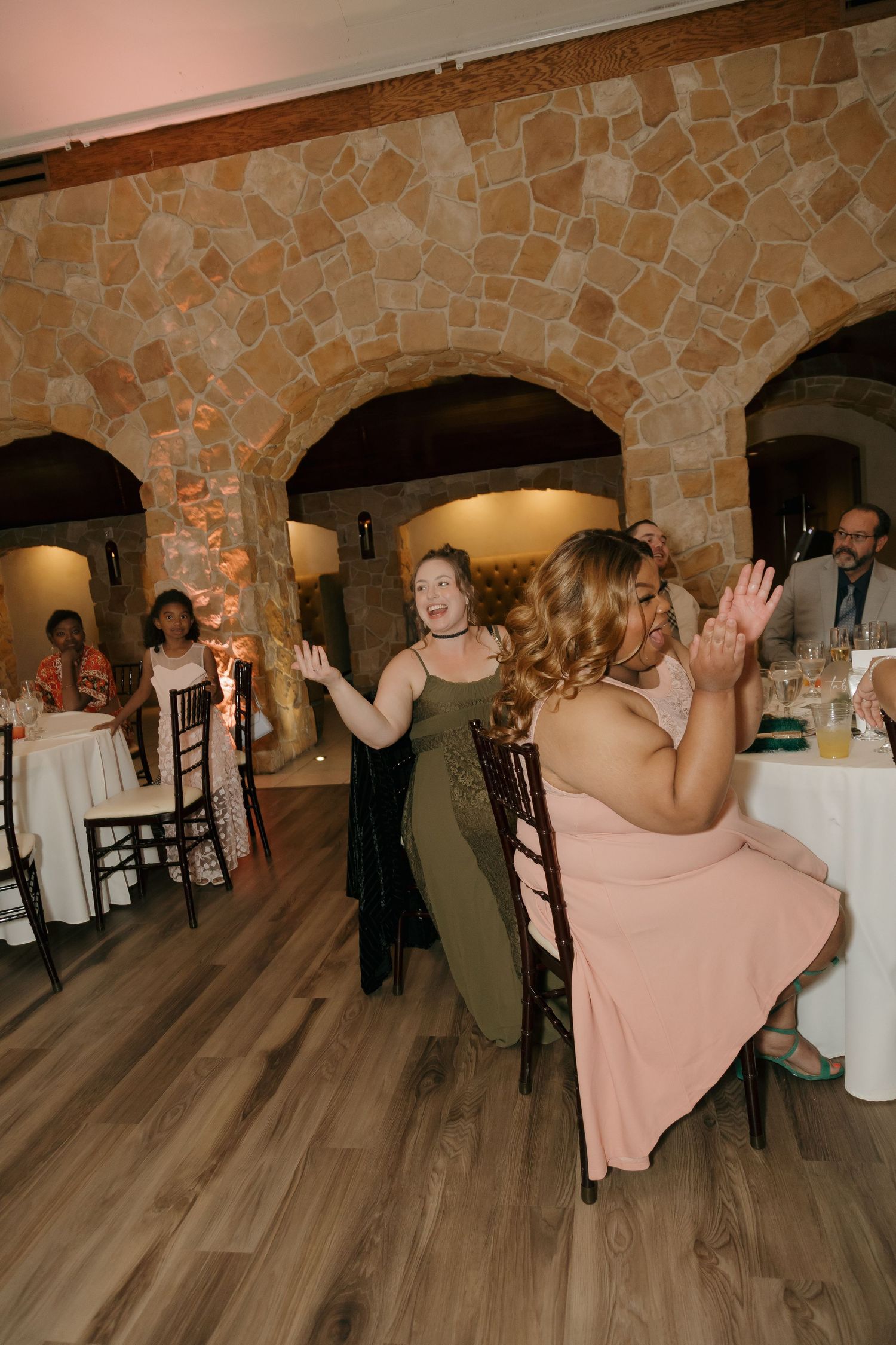 Wedding reception guests dancing and celebrating in a rustic stone-walled venue.