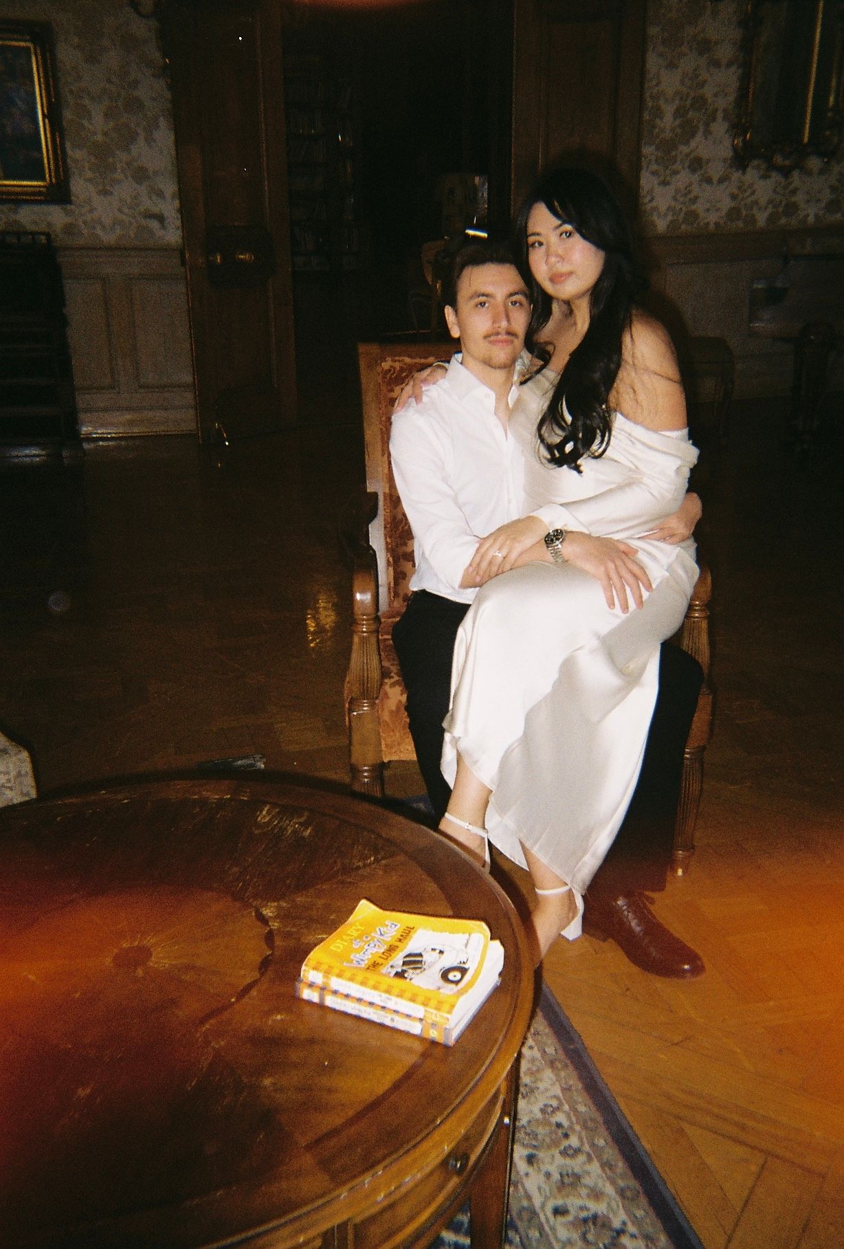 Couple shares intimate moment in vintage room with book on round table.