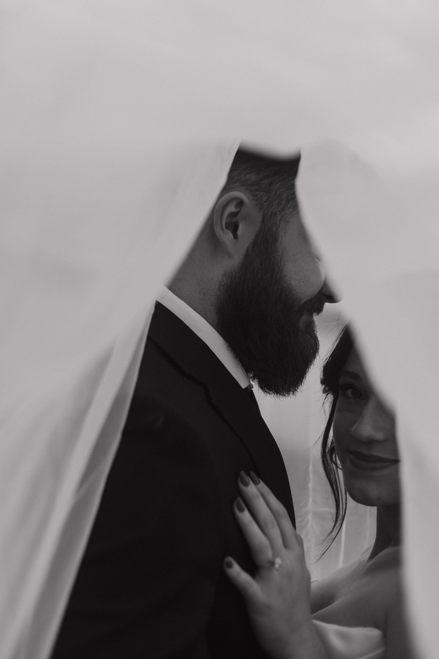Intimate black and white portrait of a couple in wedding attire sharing a tender moment.