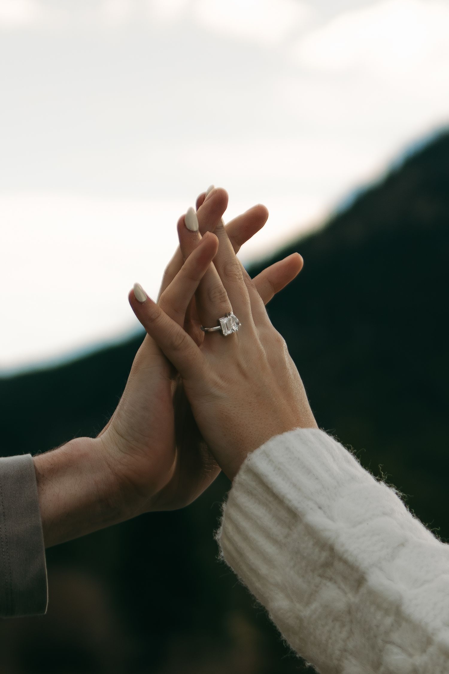 Four sequential images show hands reaching and touching against a dark mountain landscape in the background.