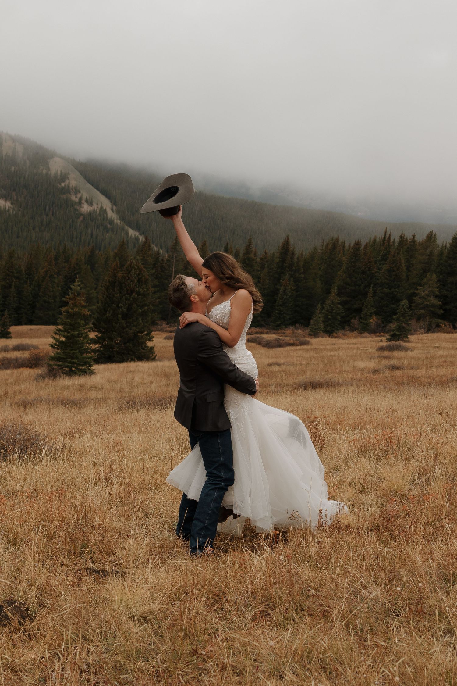 Couple dances joyfully in a misty mountain meadow during their wedding celebration.