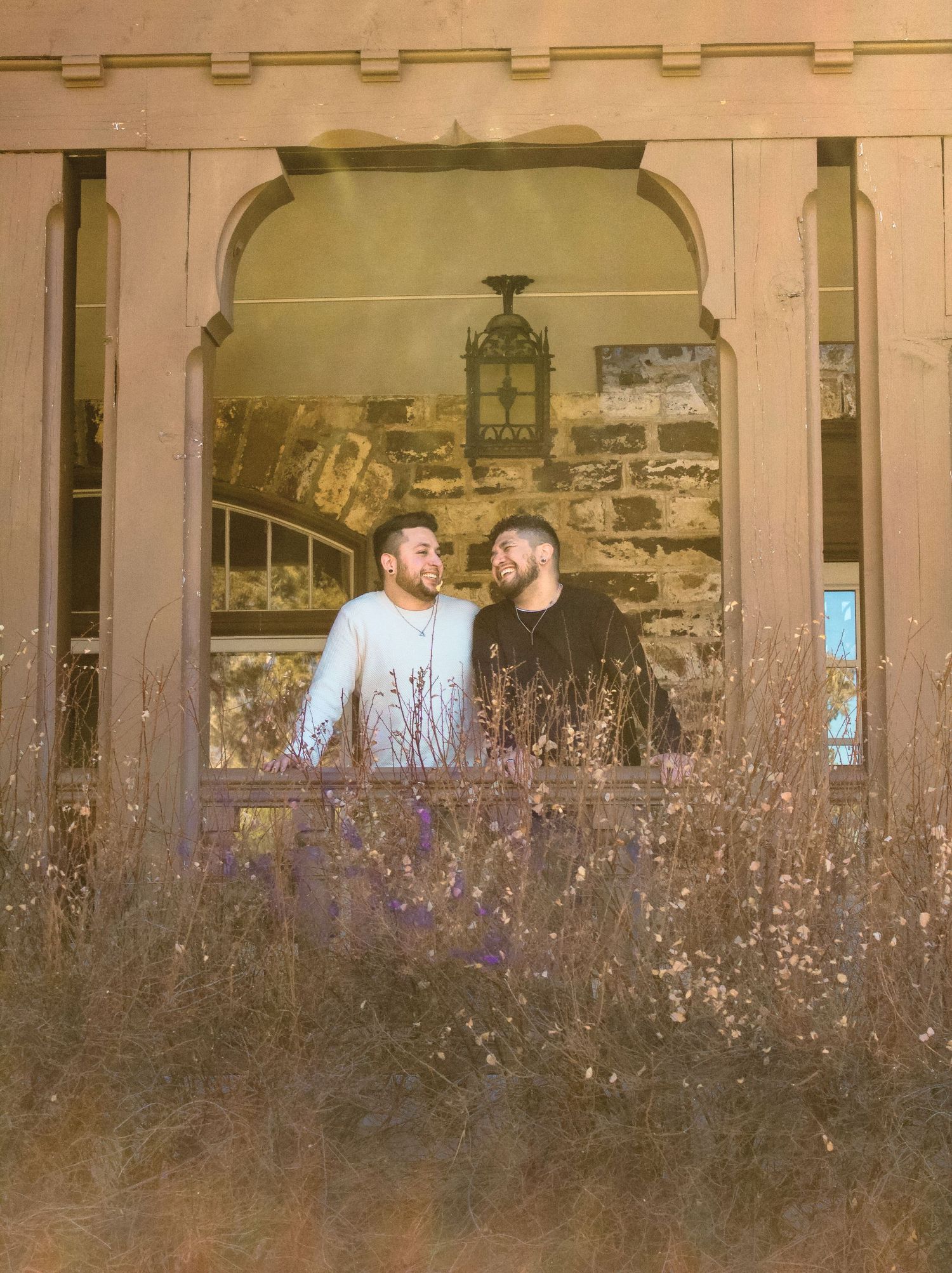 Two people sharing a romantic moment through an antique archway with dried flowers below.
