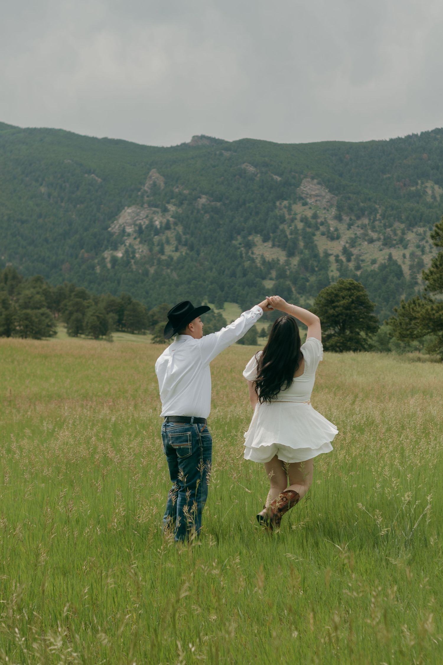 Dancing and spinning in a mountain meadow wearing casual western attire.