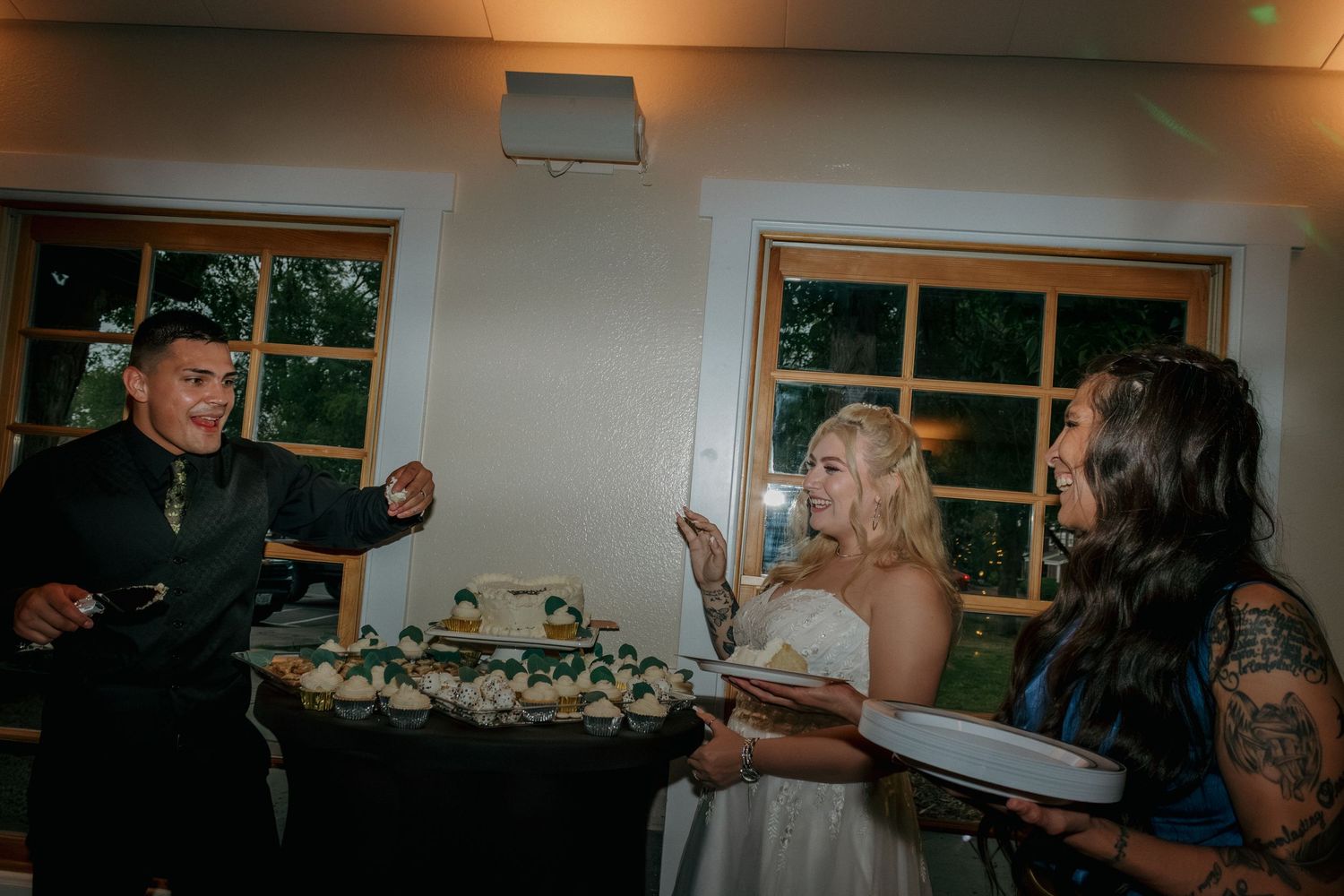 Festive cake cutting celebration at wedding reception with dessert table in background.