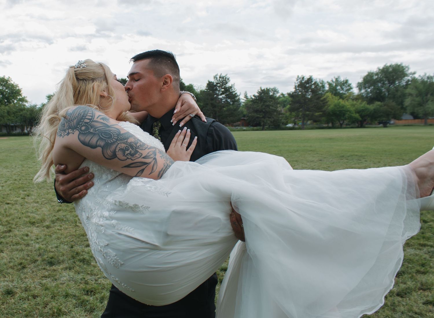 Wedding couple dances and spins in a grassy field making the white dress flow beautifully.