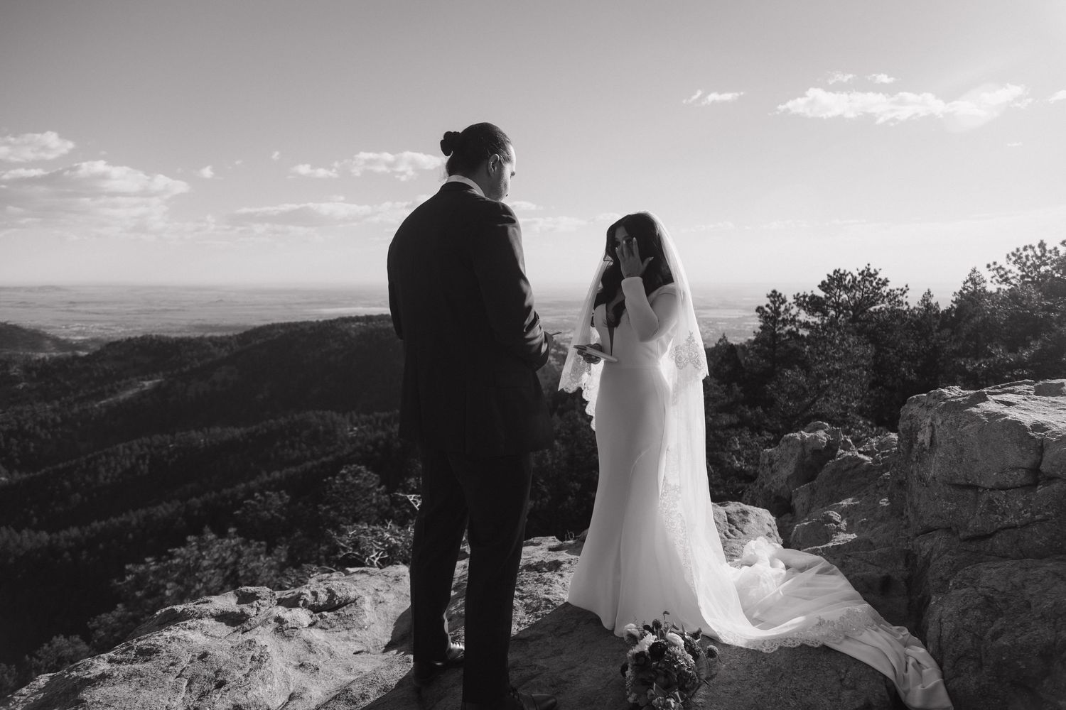 Black and white photo of bride and groom sharing emotional vows on a mountain summit.