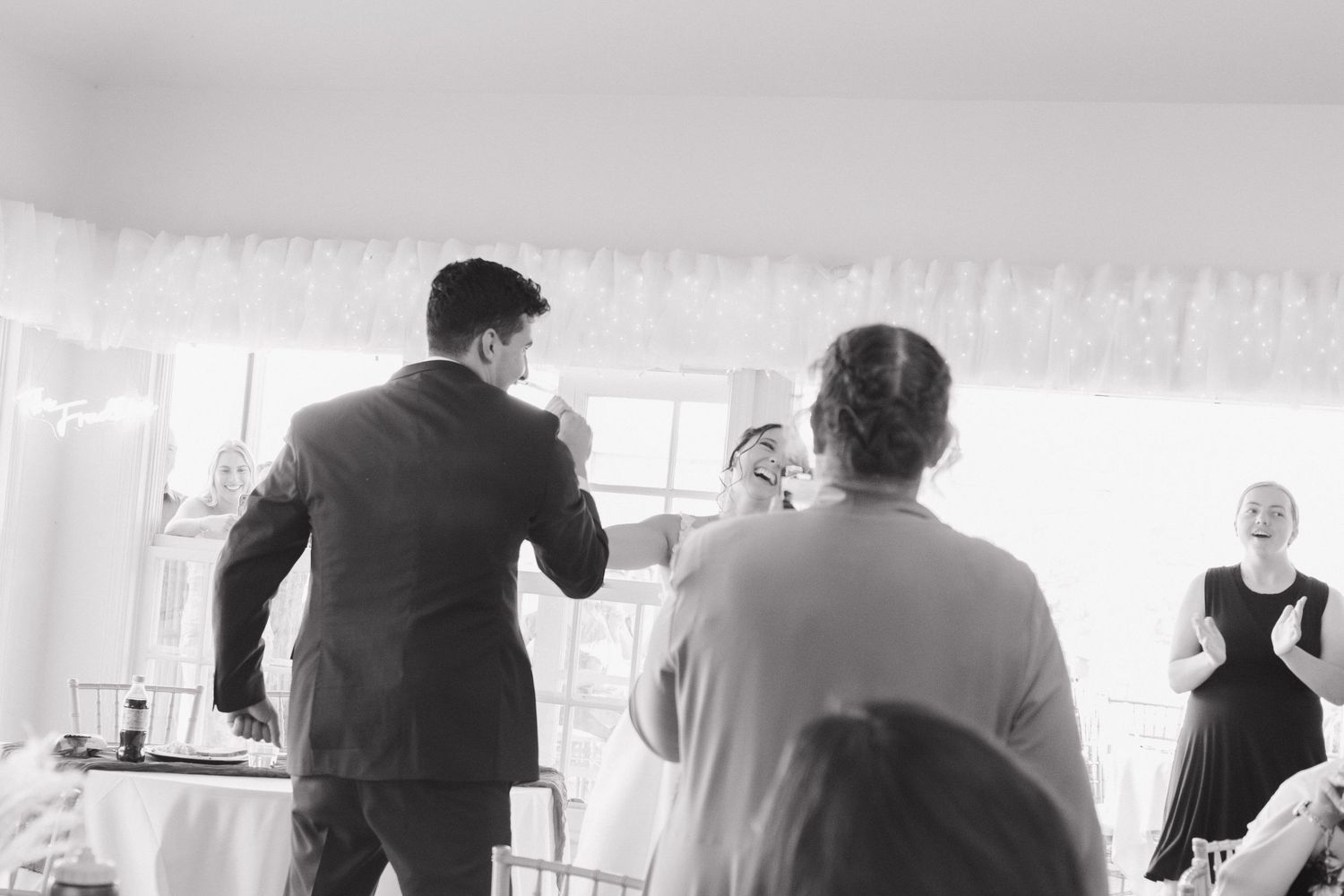 Light-filled reception space with silhouettes of guests against bright windows.