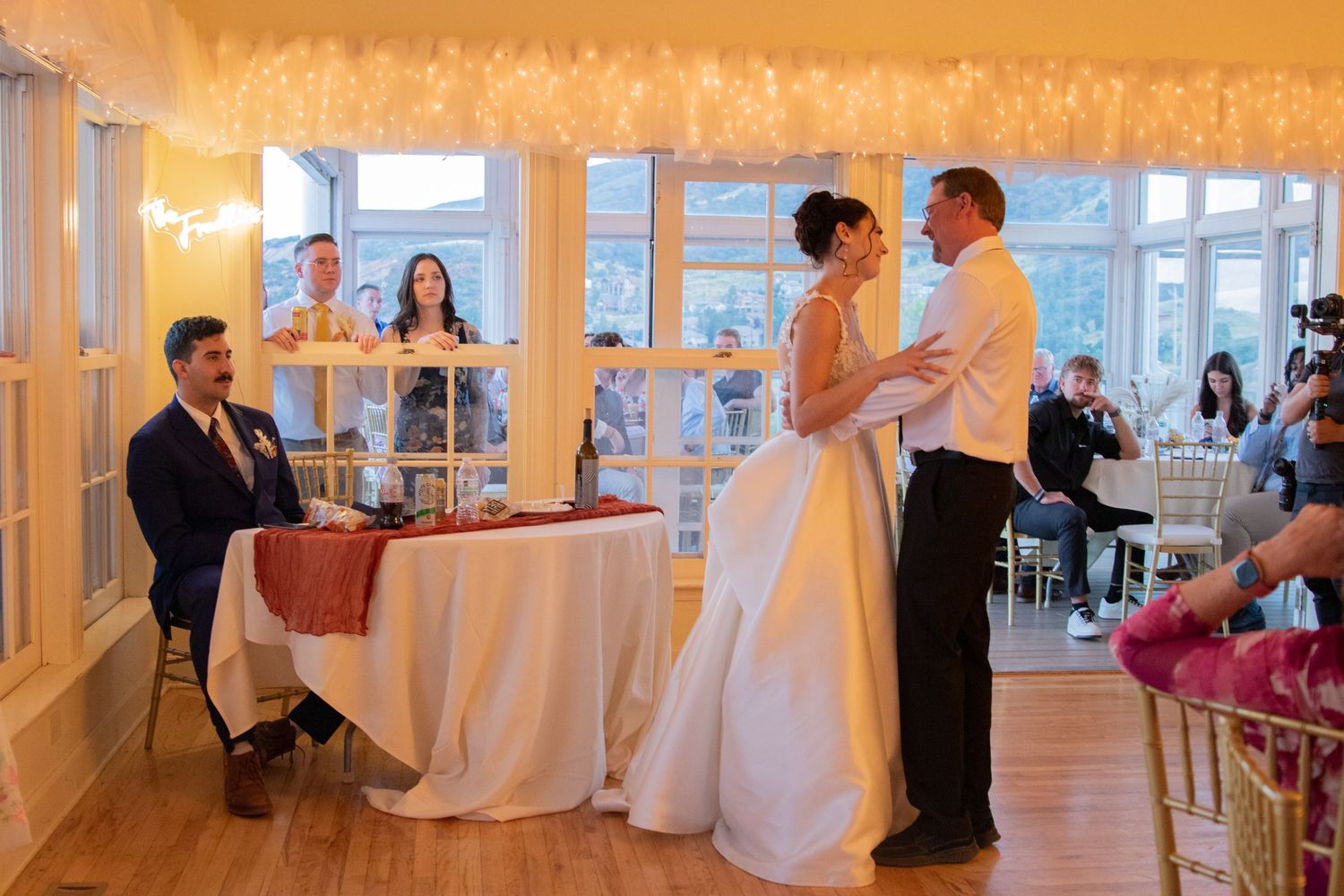 Wedding reception venue with warm lighting and white draped decorations.