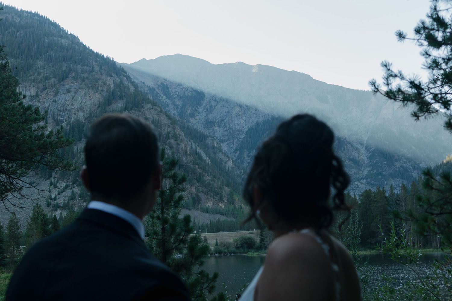 Mountain silhouettes create dramatic backdrop for wedding photography.