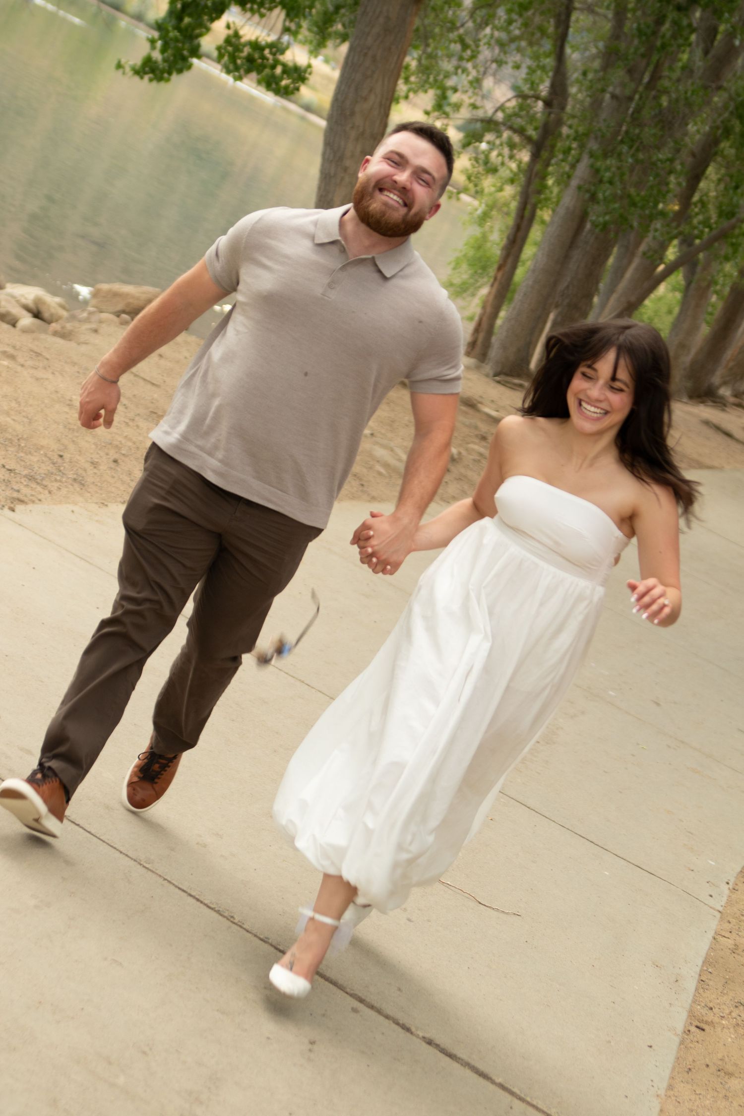 Two people in casual attire walking together on a concrete pathway with trees in the background.