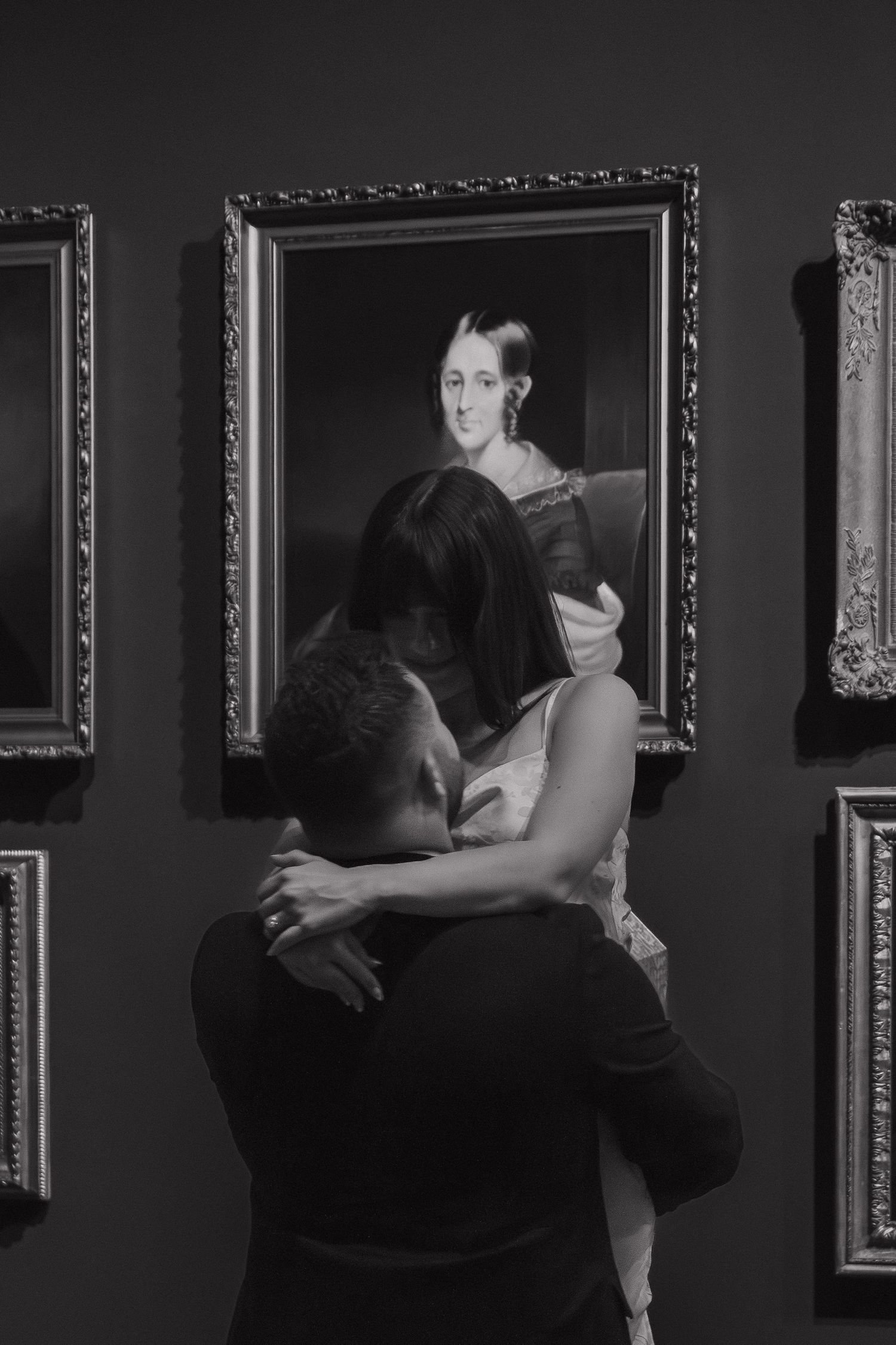 Black and white photo of dancers performing in an art gallery surrounded by framed artwork.
