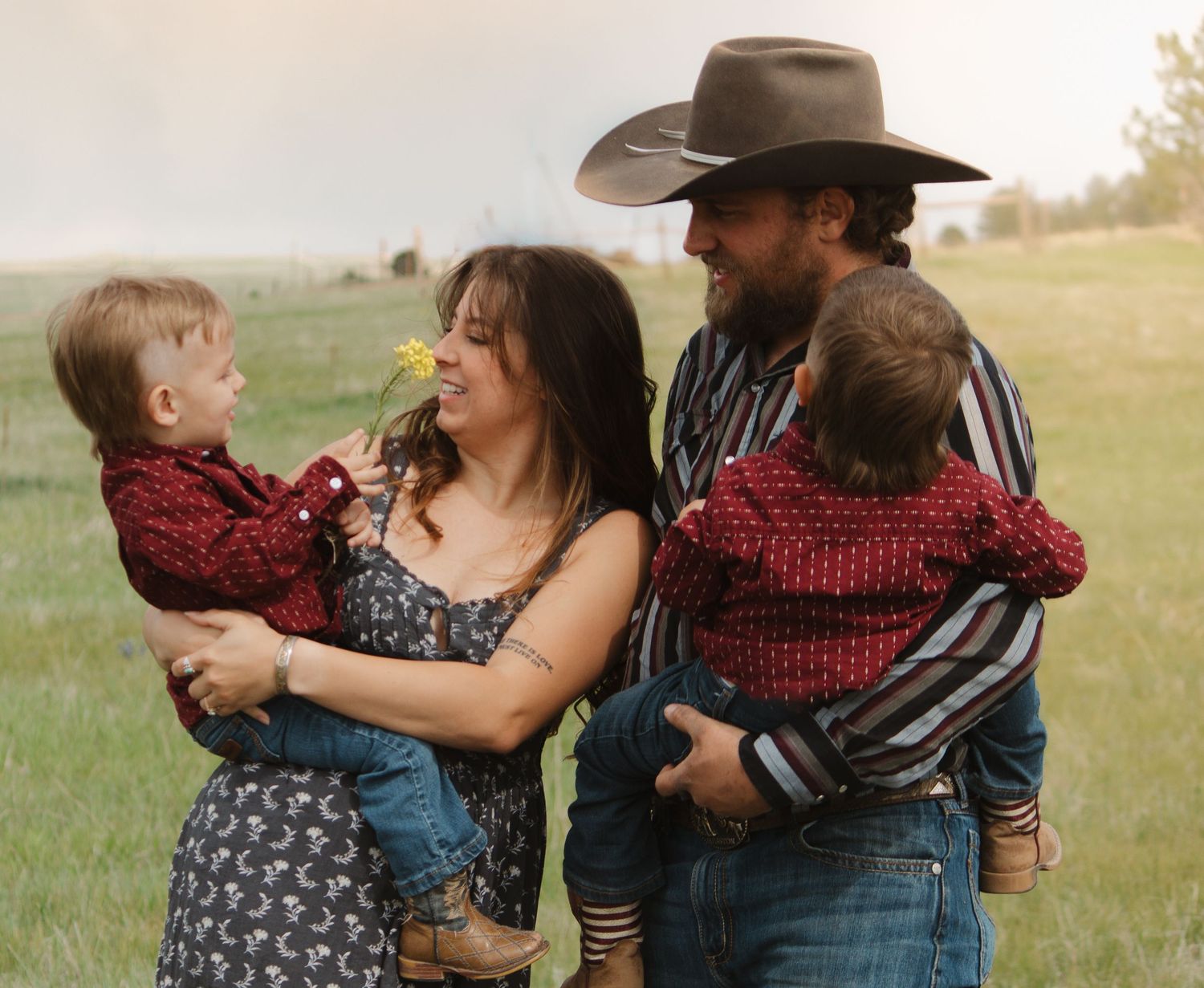 Family shares tender moment together in field wearing coordinating western outfits.