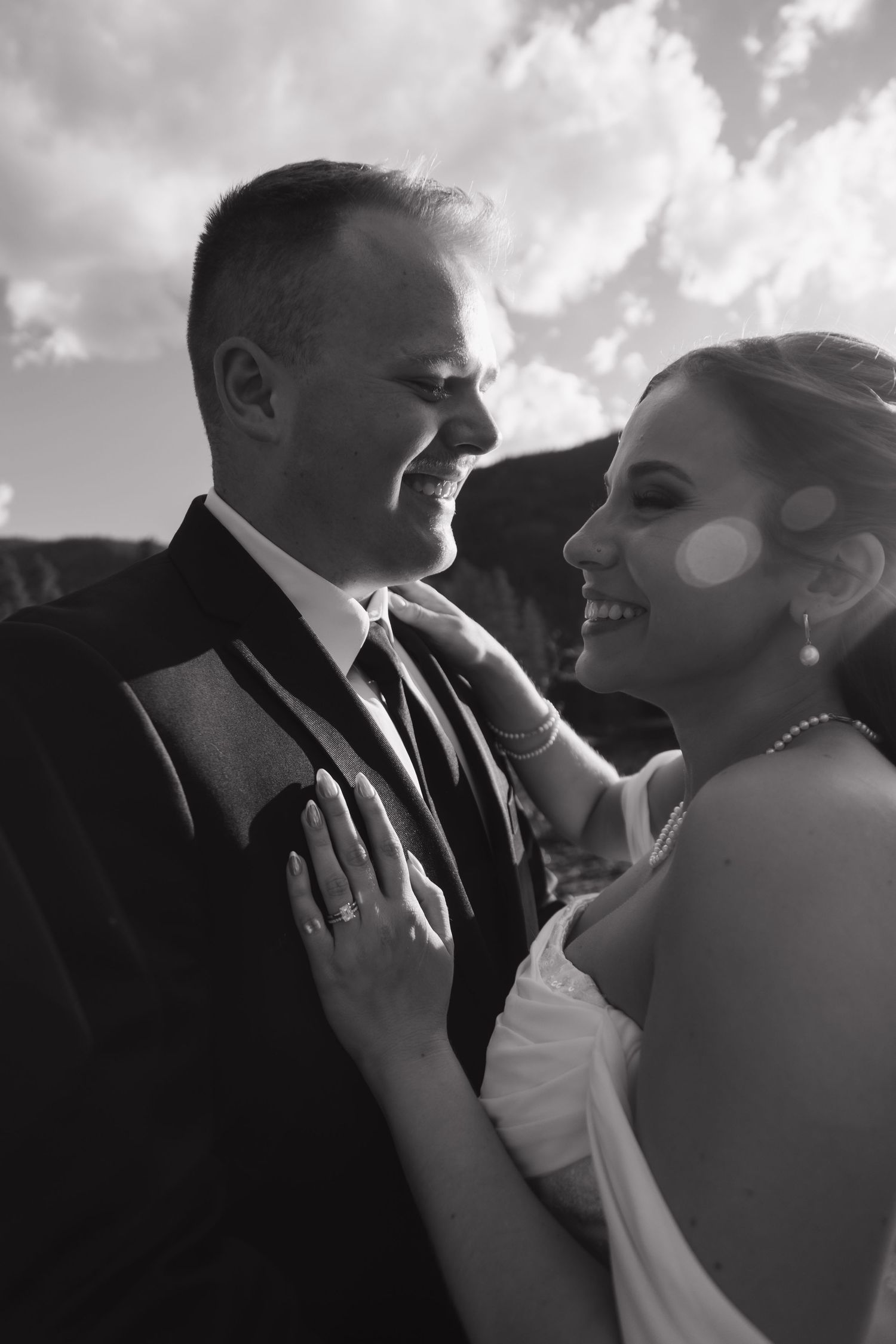 Black and white portrait of smiling bride and groom sharing a tender wedding moment.