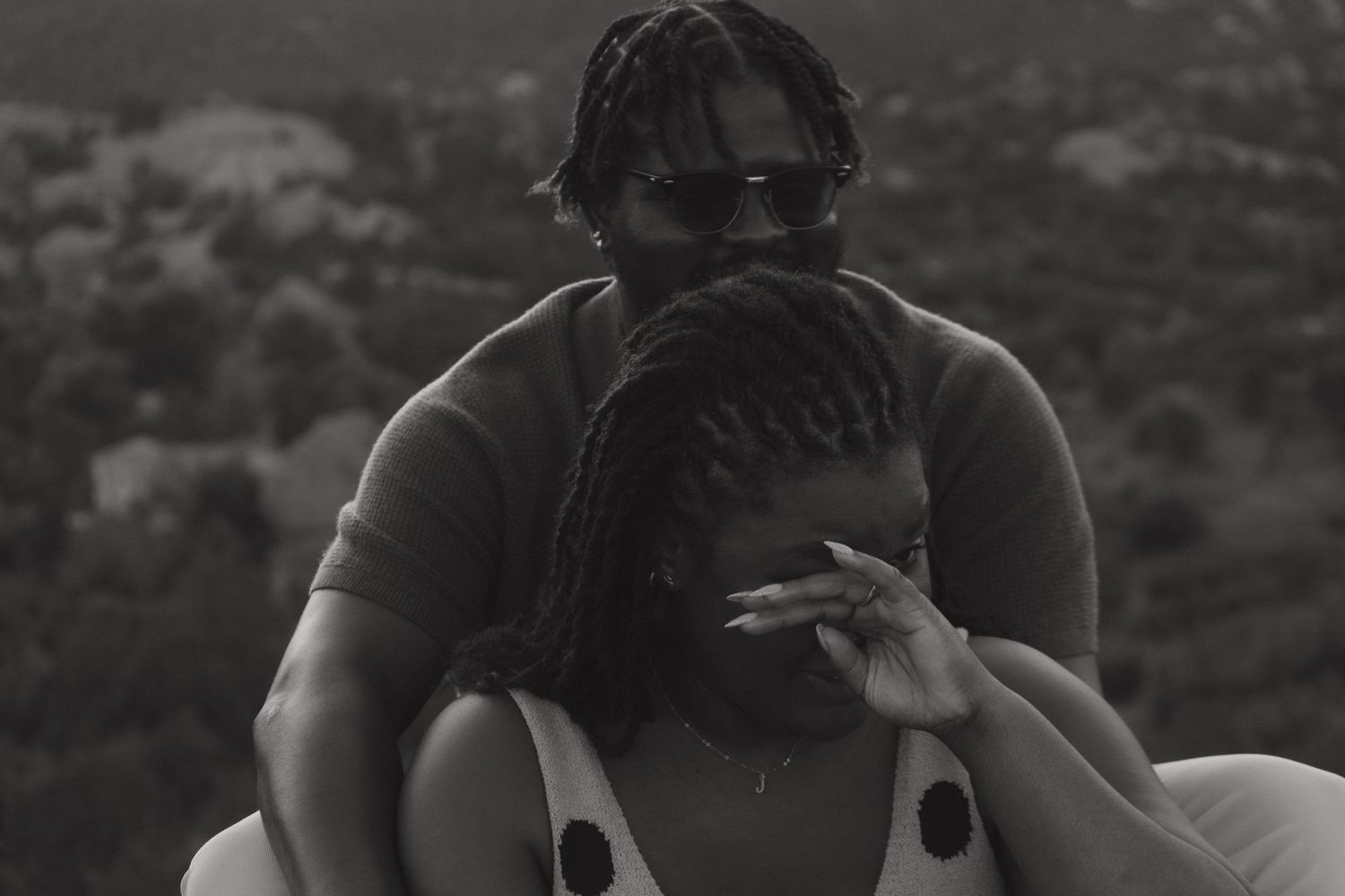 An intimate black and white portrait captured against a mountain landscape.