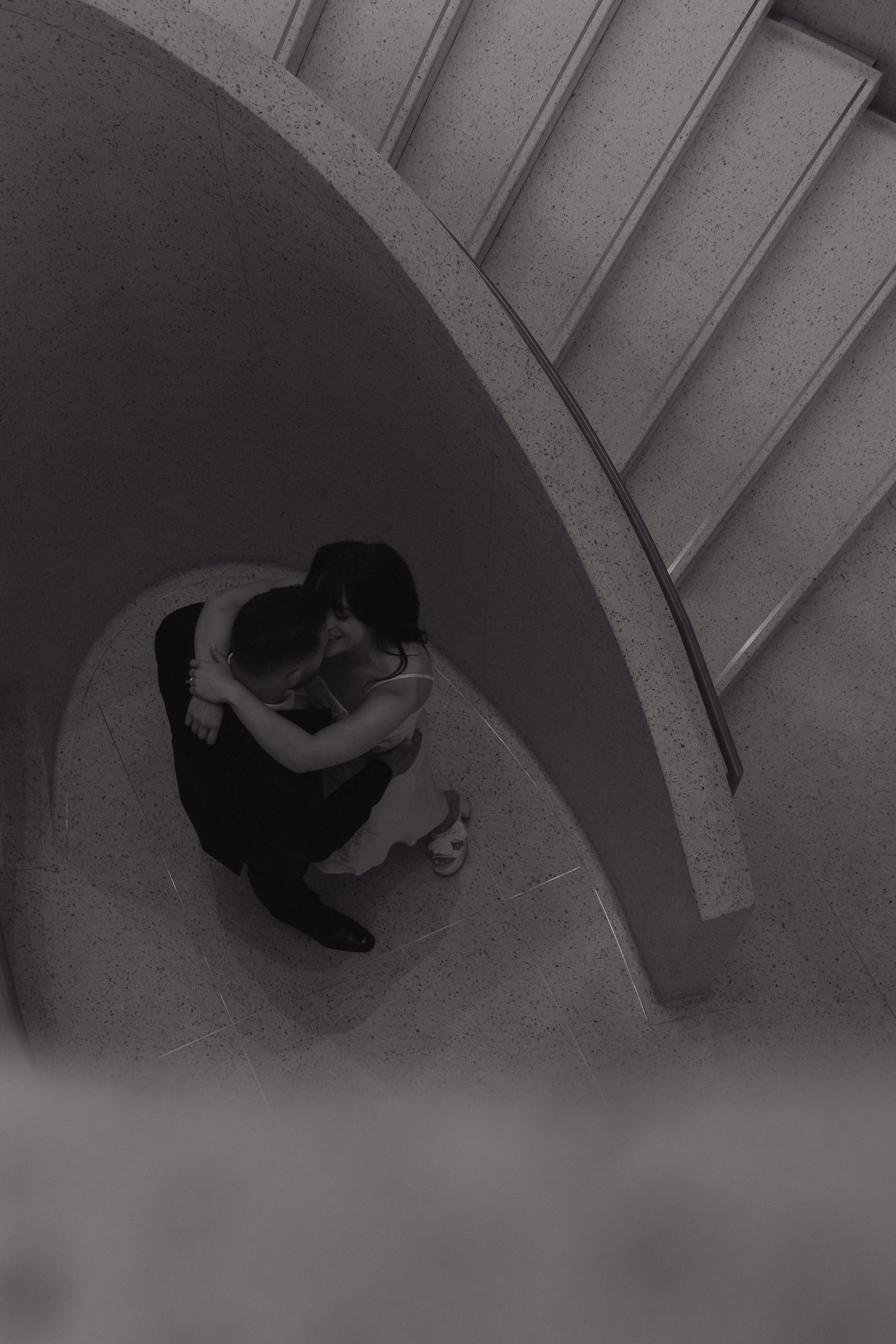 A romantic moment captured from above in a curved architectural space.
