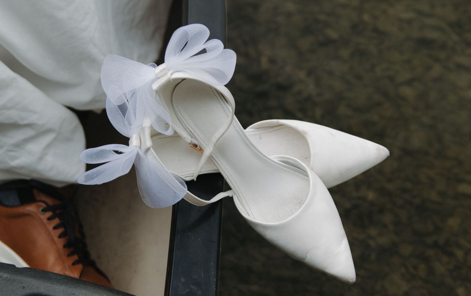 Elegant white bridal shoes with delicate bow details displayed in a row.