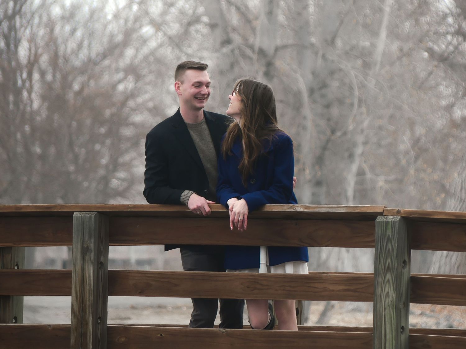 A couple sharing a romantic moment on a wooden bridge during winter.
