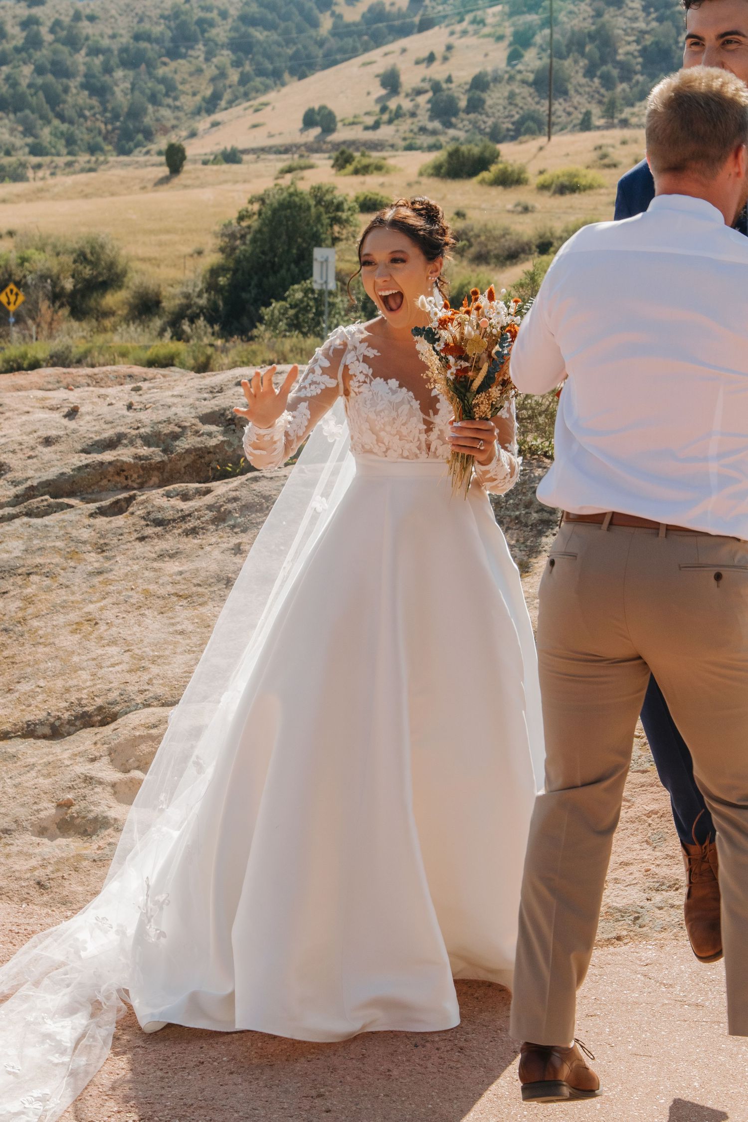 A white wedding dress flowing in the breeze against a mountainous desert landscape.
