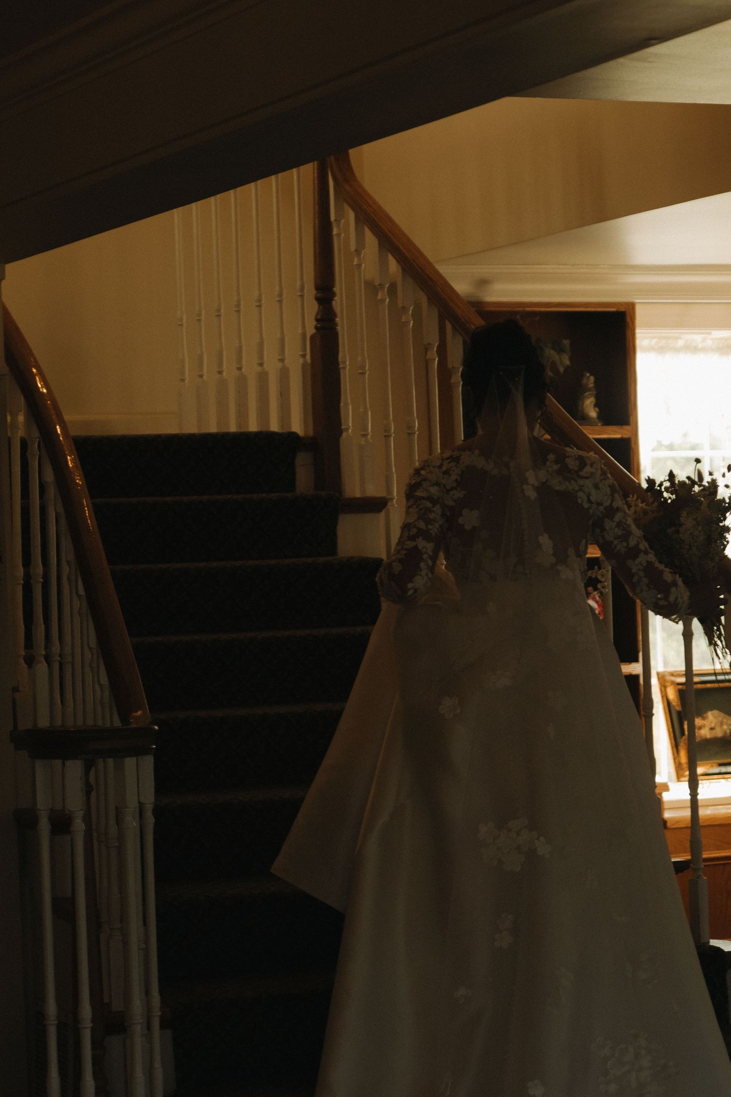 Silhouette of a wedding dress ascending a dark staircase in dramatic lighting.