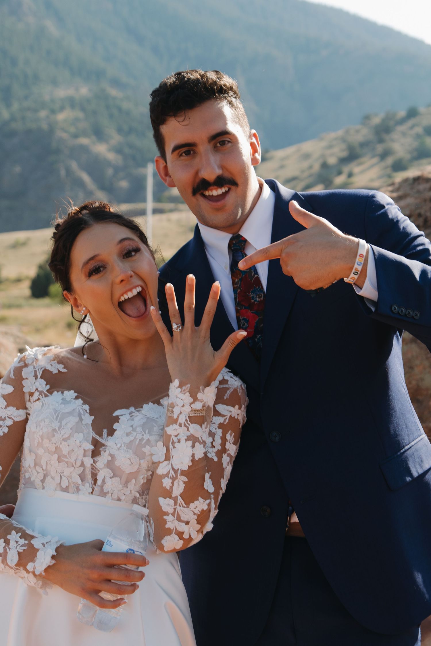 A playful wedding photoshoot moment captured against mountain scenery.