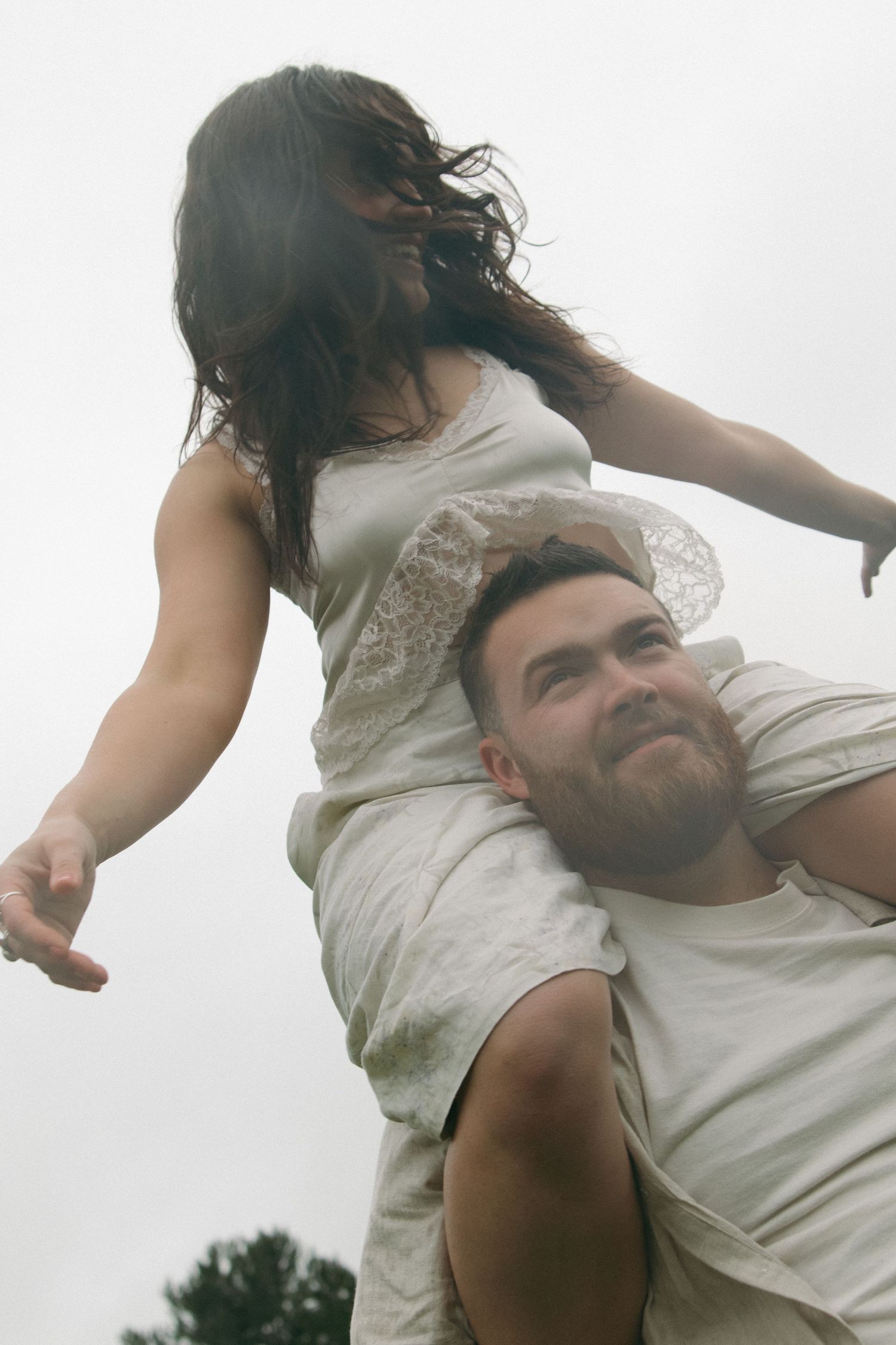 A creative upward angle shot of a couple during a playful outdoor photography session.