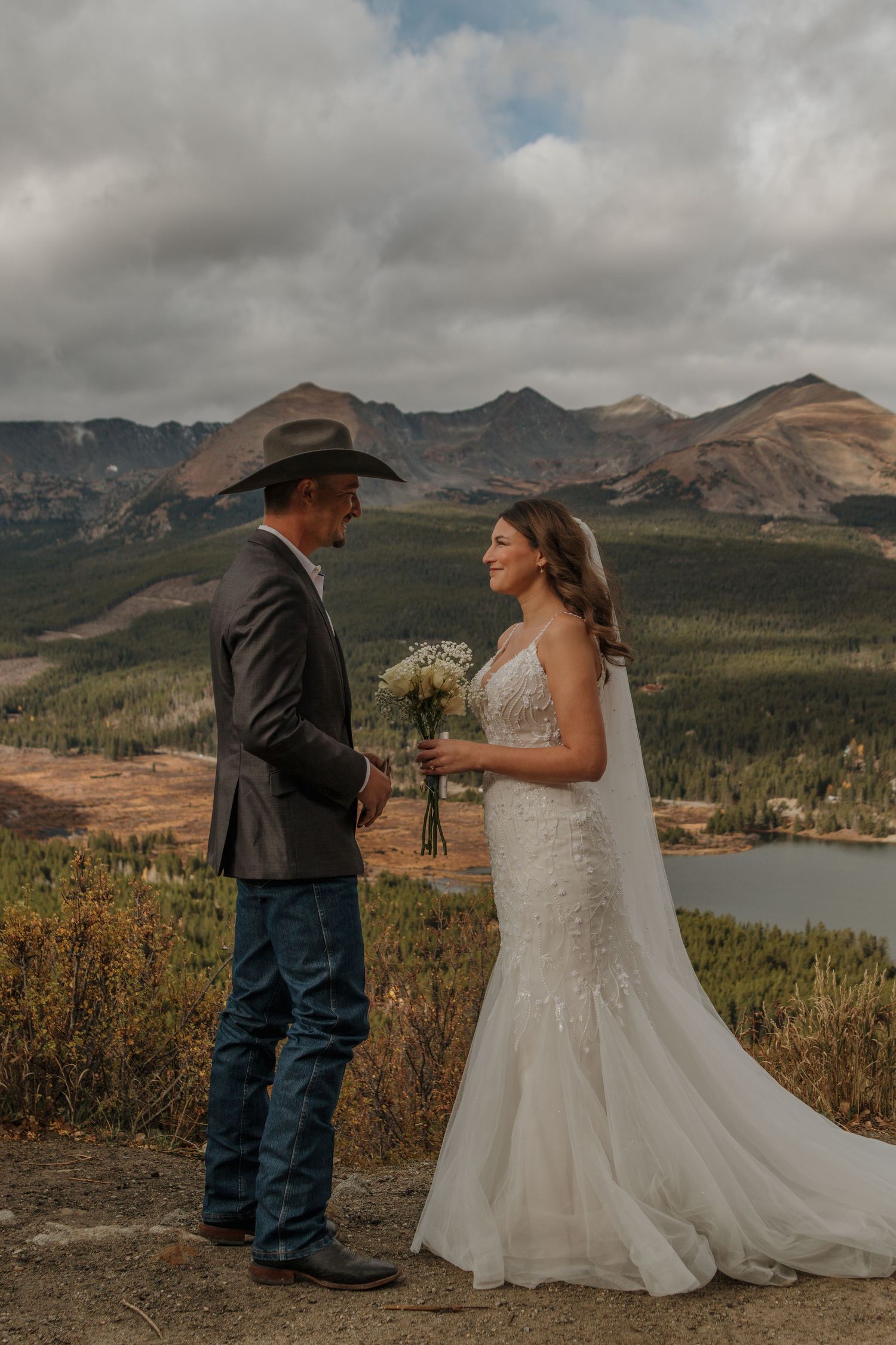 A couple exchanges vows during their mountain wedding with sweeping valley views.