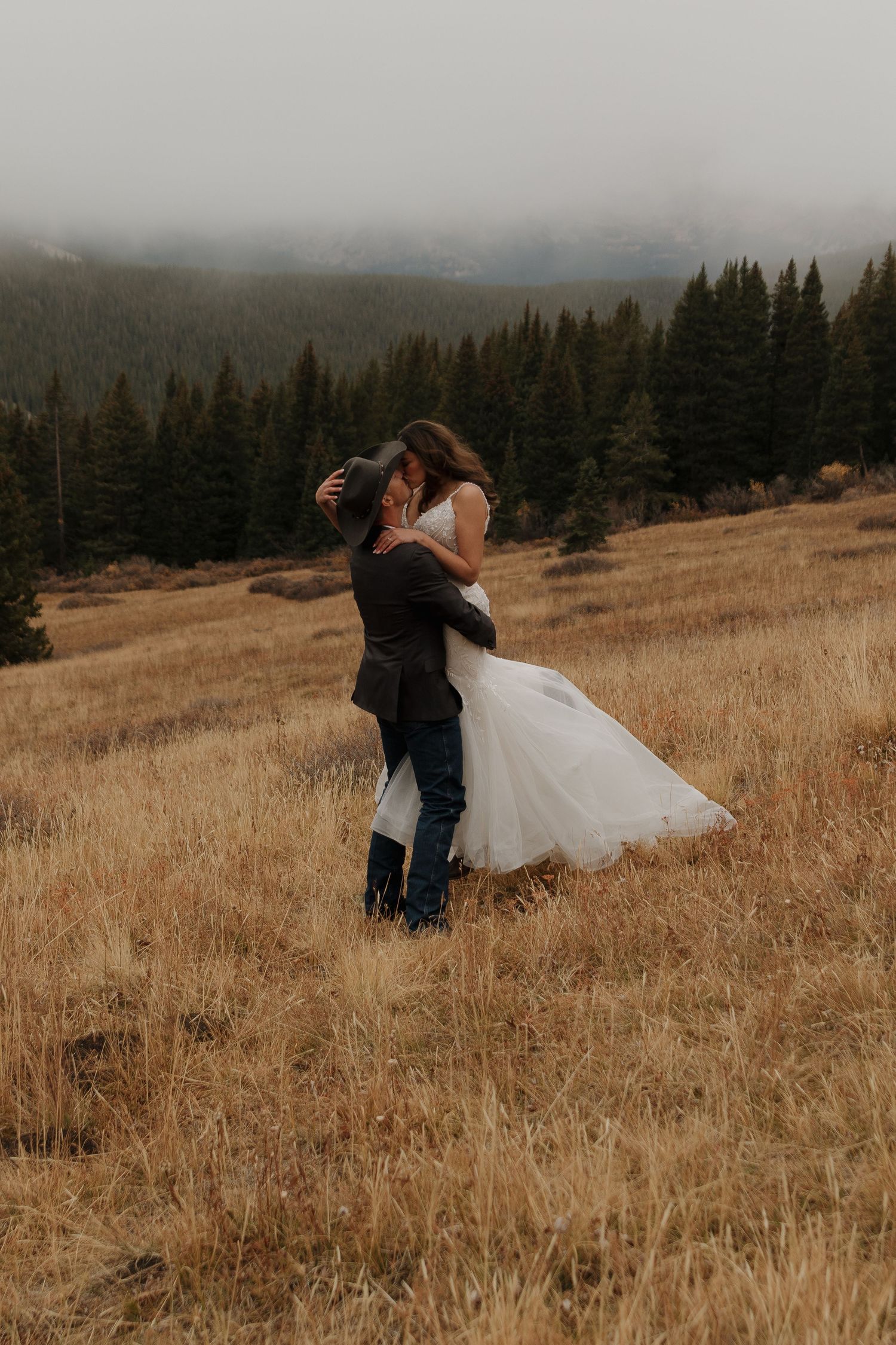 A romantic embrace in a misty mountain meadow during golden hour.