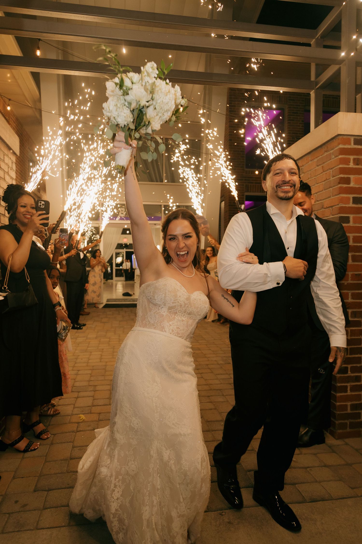 Bride and groom celebrating grand exit with sparkling cold sparklers at wedding reception.