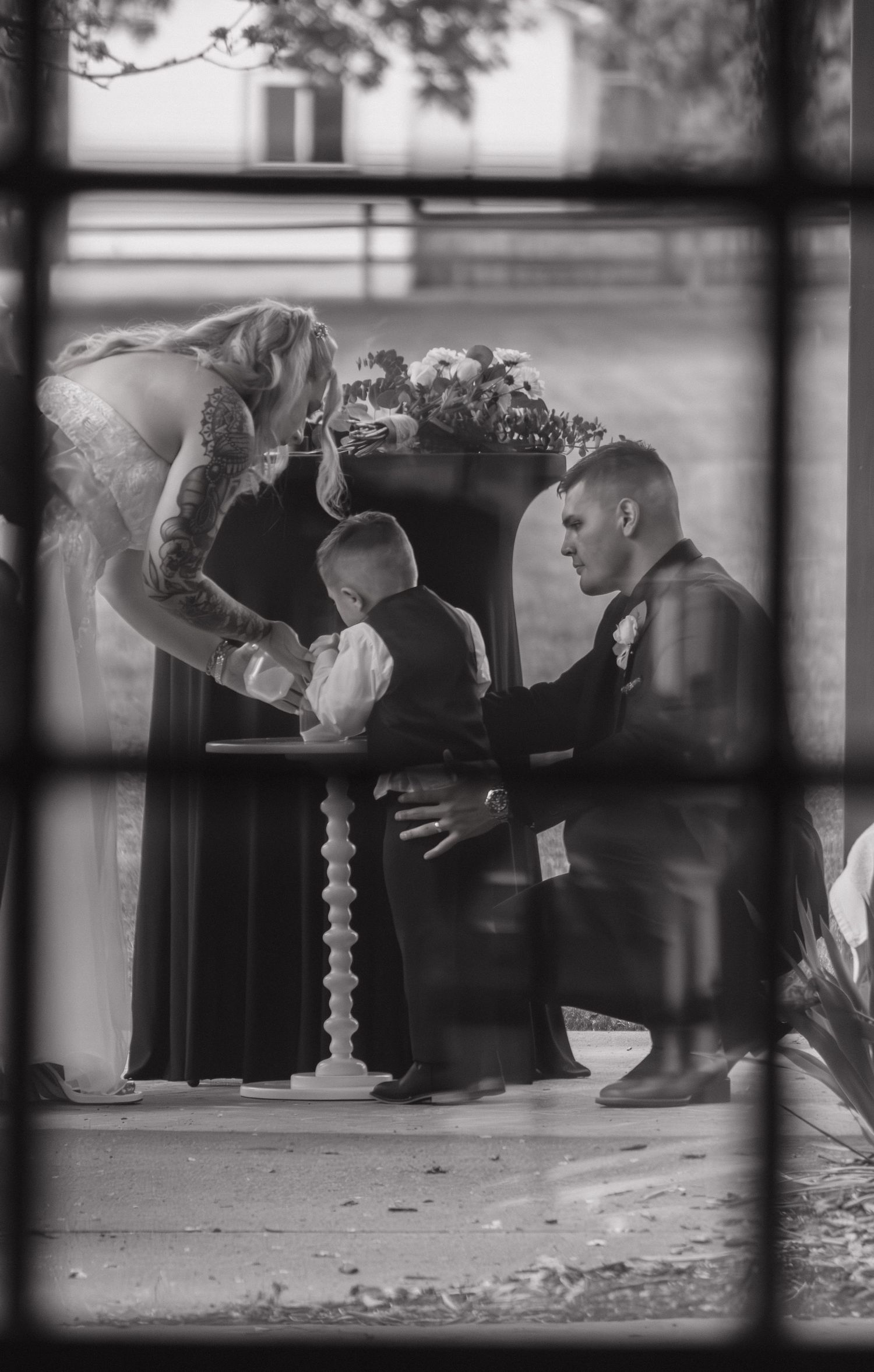 A tender moment during a wedding ceremony viewed through window frames.