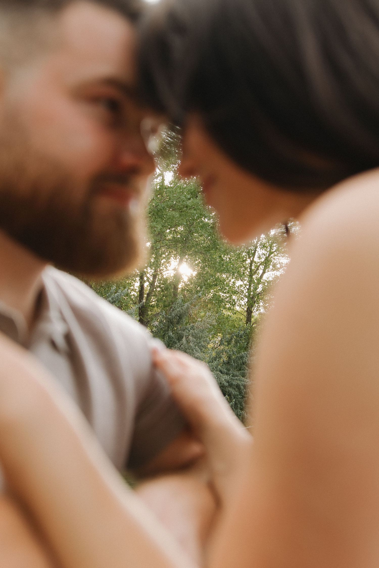 An intimate couple sharing a tender moment outdoors in natural sunlight.