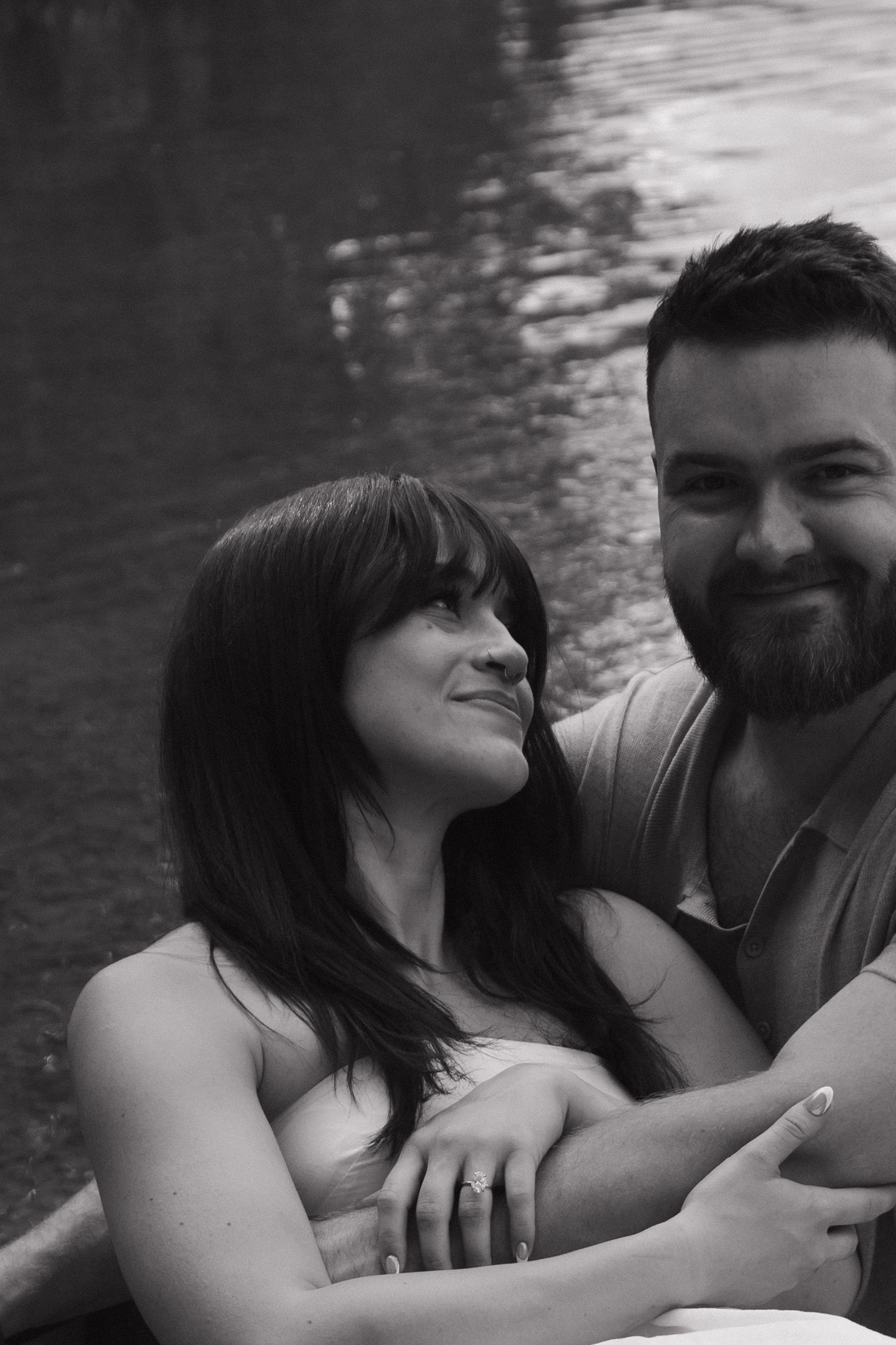 A romantic couple shares tender moments by the water in a series of black and white photographs.